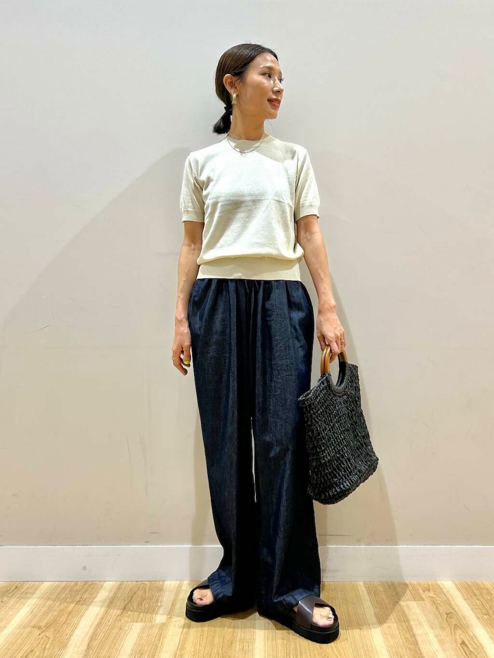 ブラック系のトートバッグ、ブラウン系のサンダル、ホワイト系のニット/セーターを着用したレディースの夏コーディネートの2枚目の写真