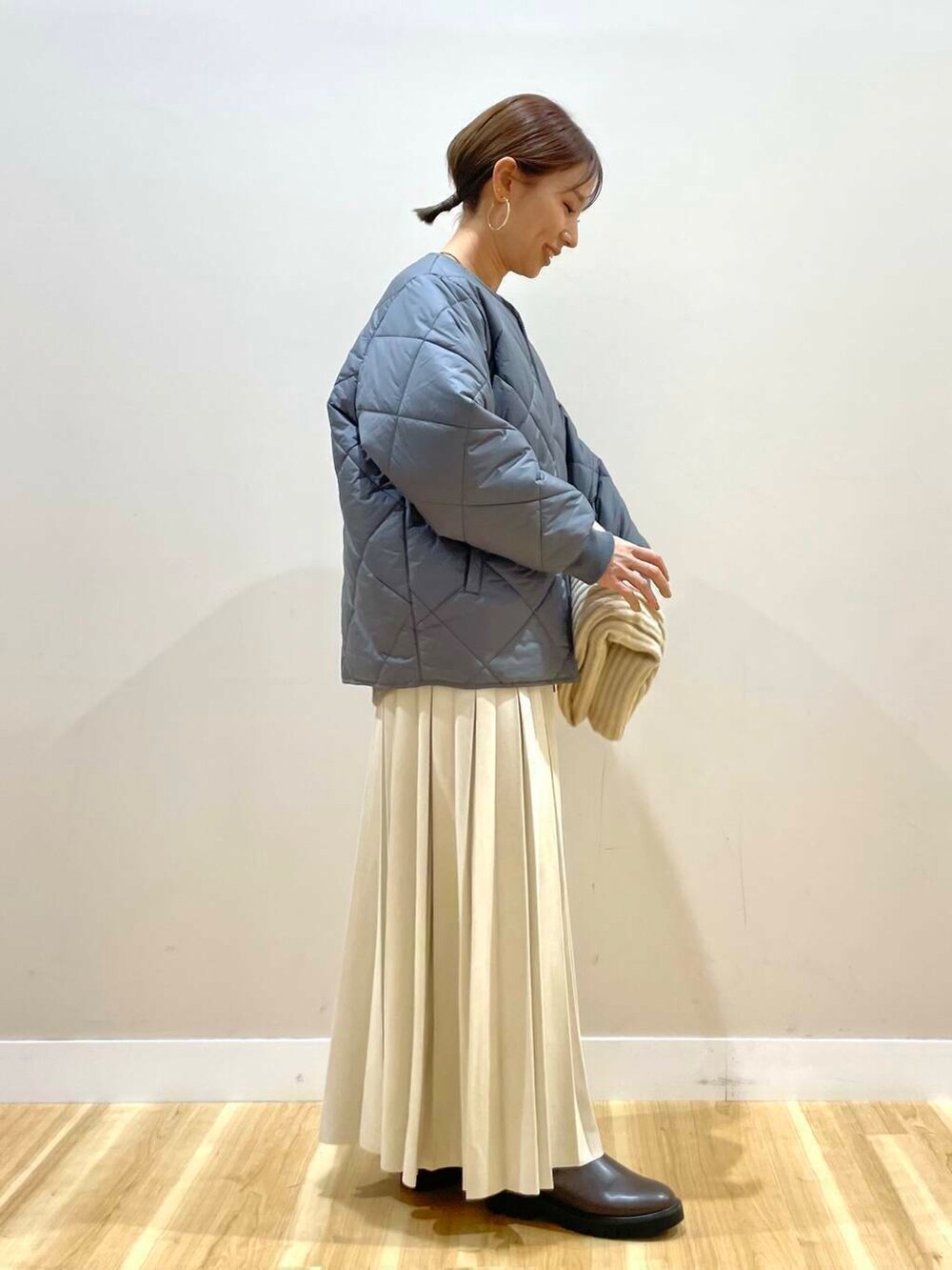 ベージュ系のスカート、ブラック系のブーツ、グレー系のダウンジャケット/コートを着用したレディースの冬コーディネートの2枚目の写真