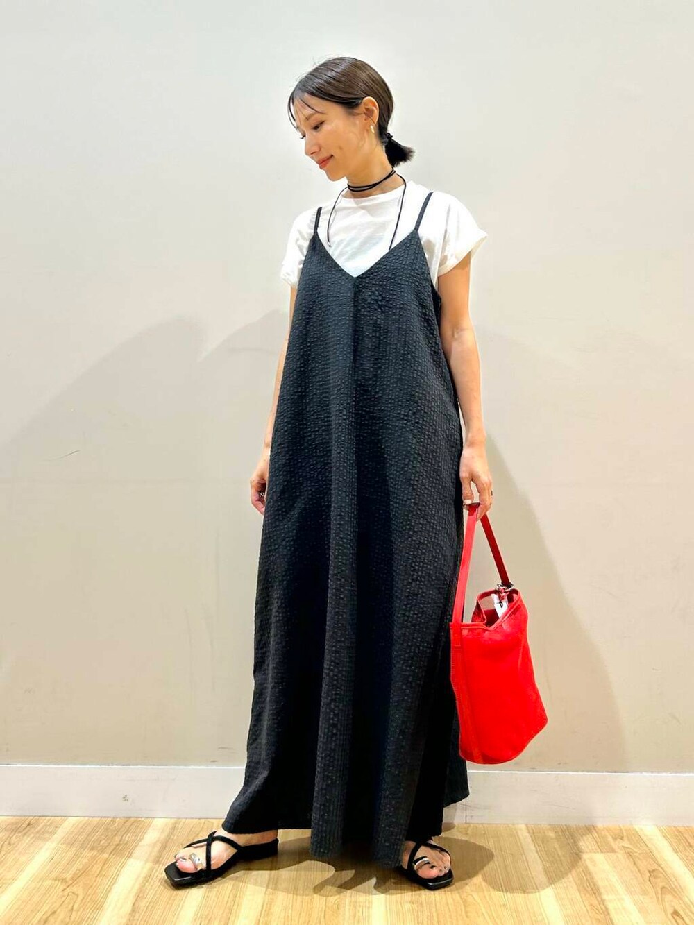 レッド系のショルダーバッグ、ブラック系のサンダル、ブラック系のワンピースを着用したレディースの夏コーディネートの5枚目の写真