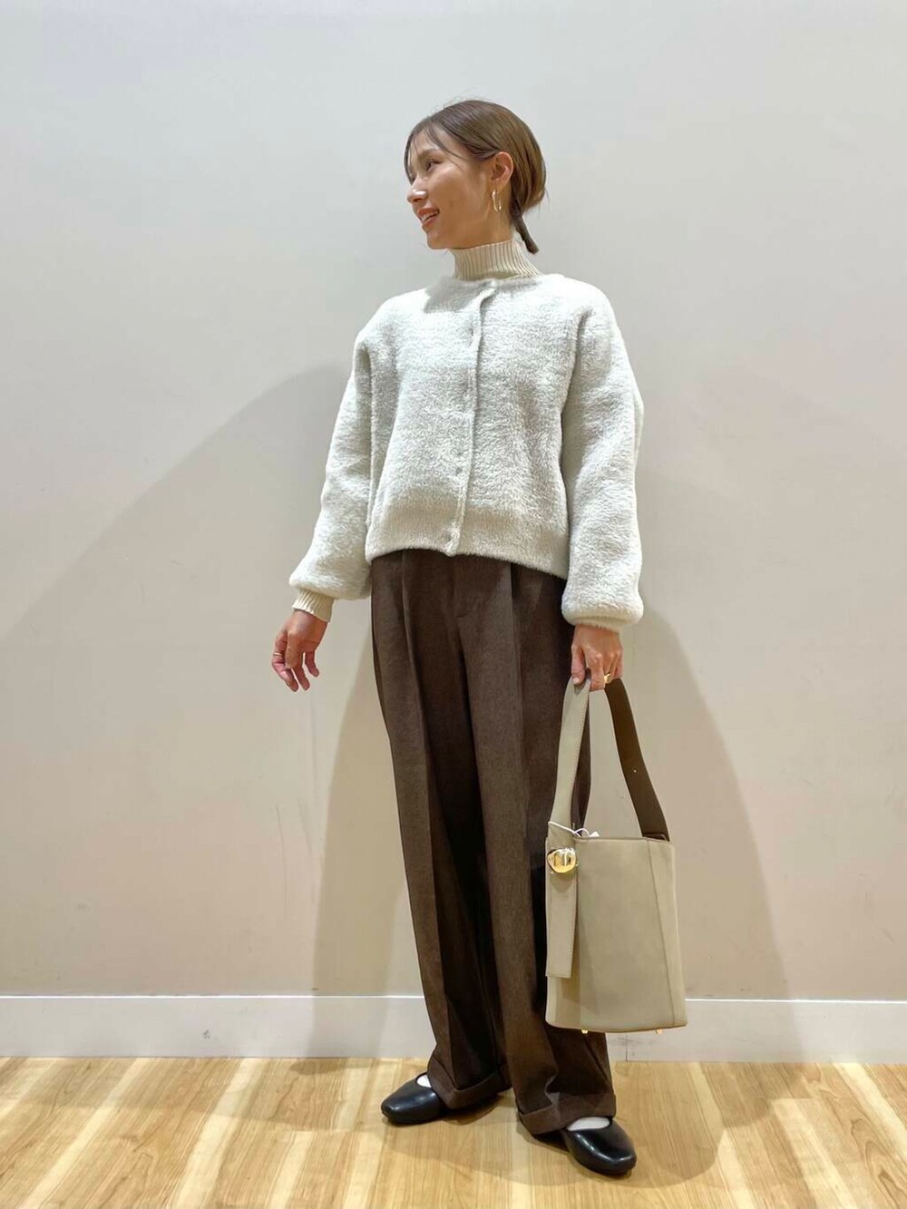 ブラック系のパンプス、ホワイト系のニット/セーター、ベージュ系のハンドバッグを着用したレディースの冬コーディネートの4枚目の写真