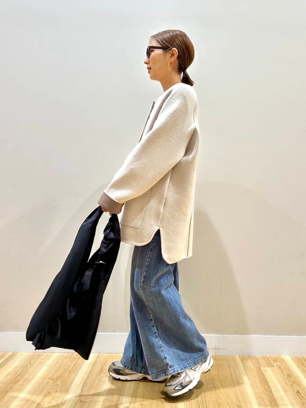 ホワイト系のニット/セーター、ブルー系のデニムパンツ、ブラック系のトートバッグを着用したレディースの春コーディネートの2枚目の写真