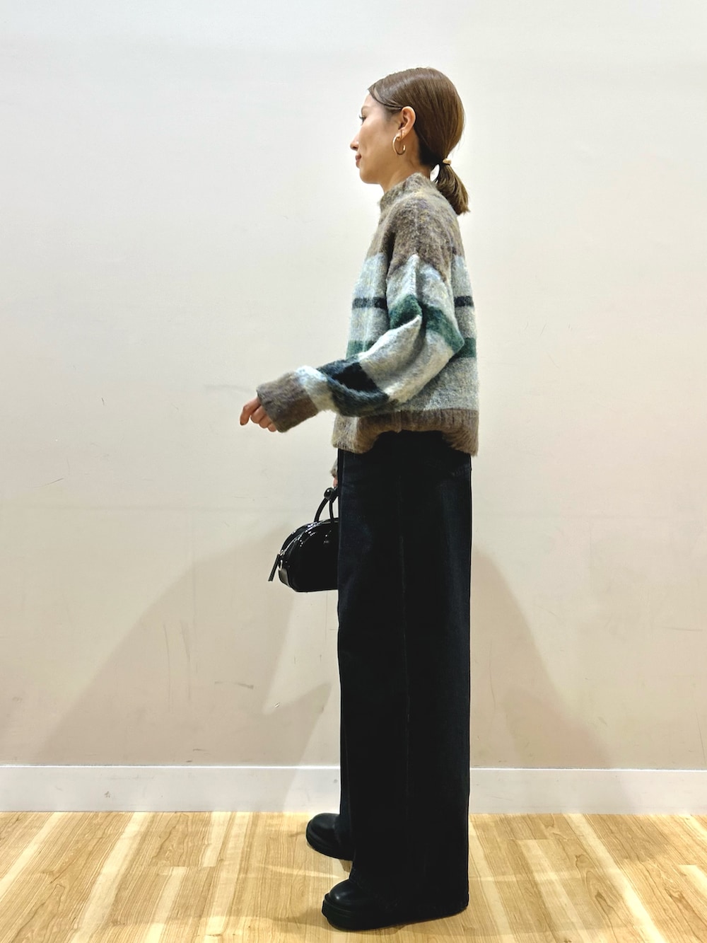 ブラウン系のニット/セーター、ブラック系のデニムパンツ、ブラック系のボストンバッグを着用したレディースの秋コーディネートの2枚目の写真