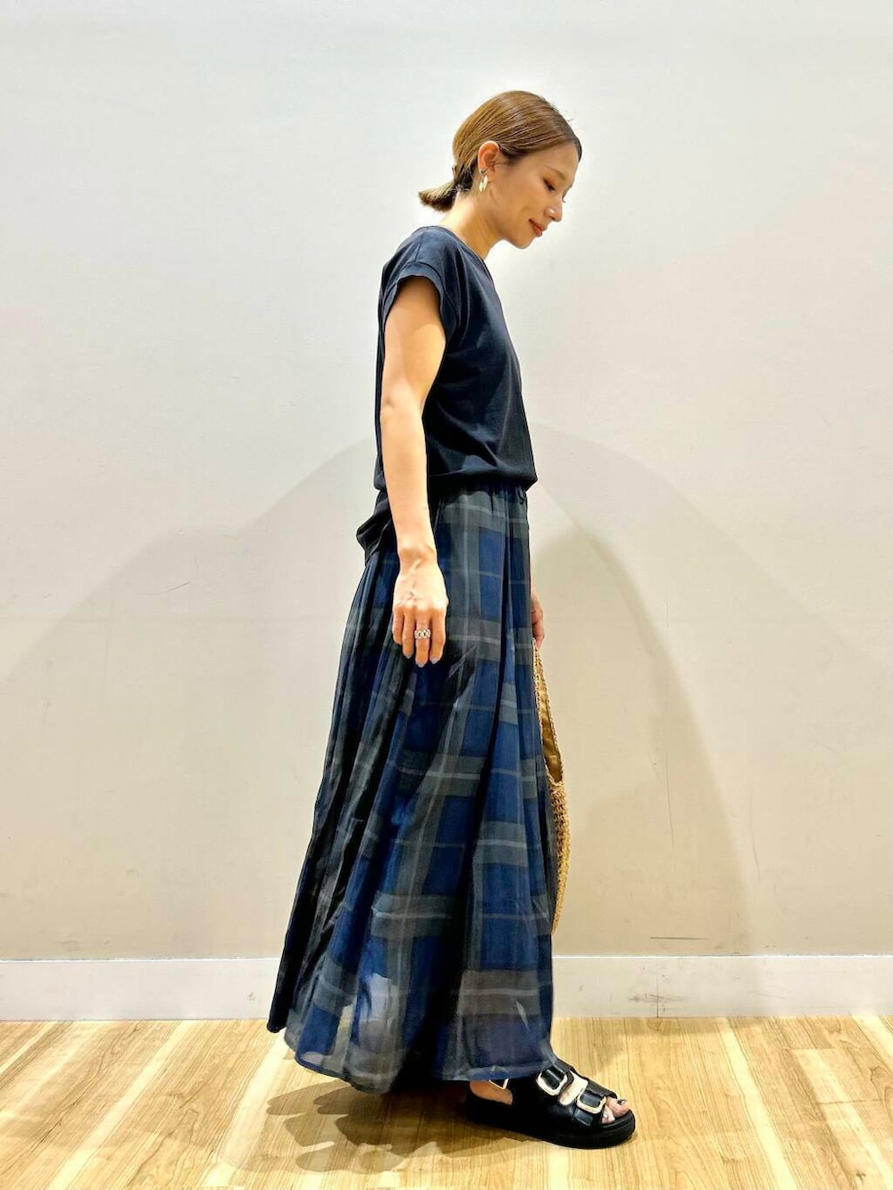 ブラック系のサンダル、イエロー系のトートバッグ、ブルー系のスカートを着用したレディースの夏コーディネートの2枚目の写真