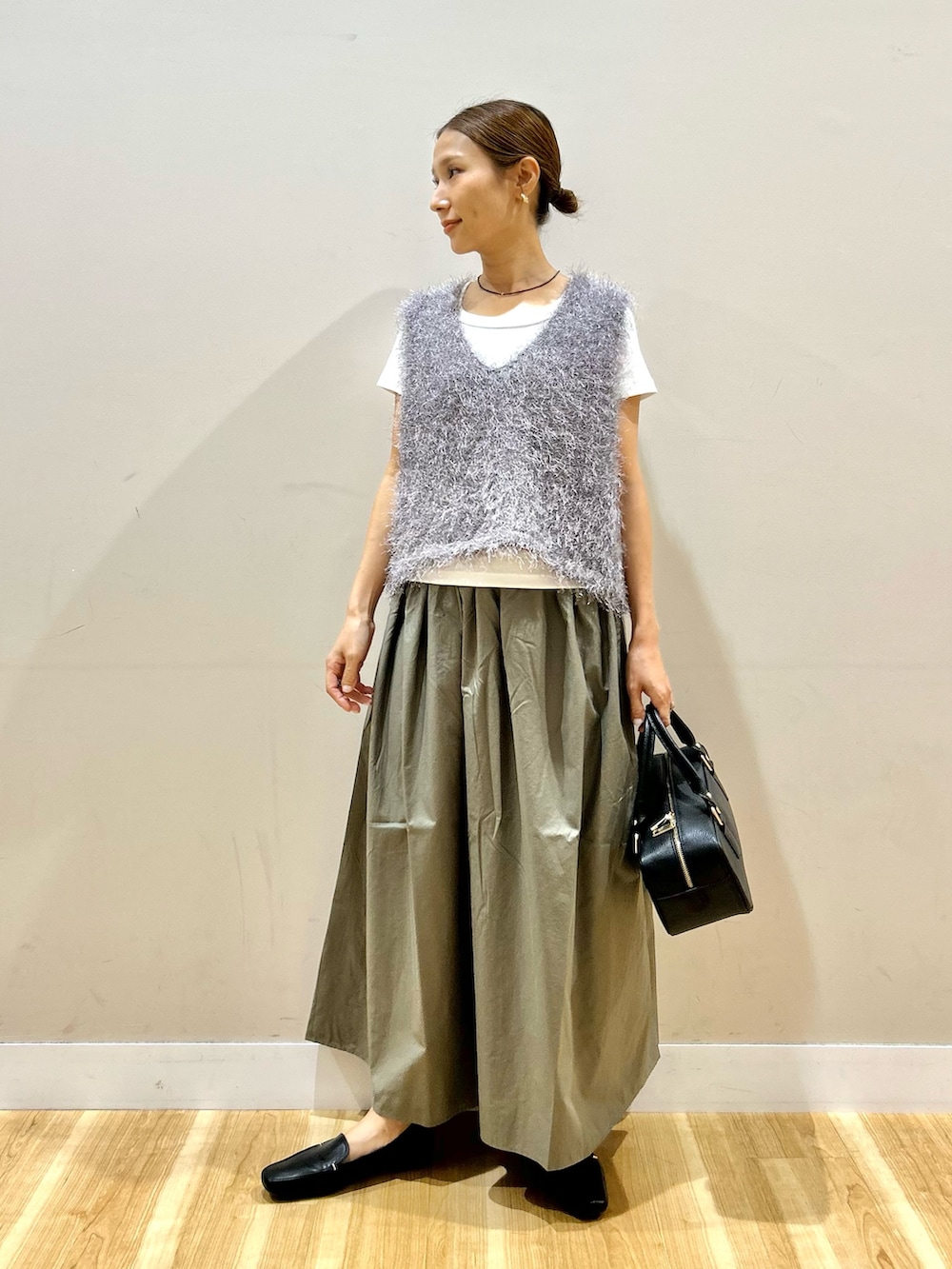 グレー系のベスト、ホワイト系のTシャツ/カットソー、グリーン系のスカートを着用したレディースの夏コーディネートの4枚目の写真