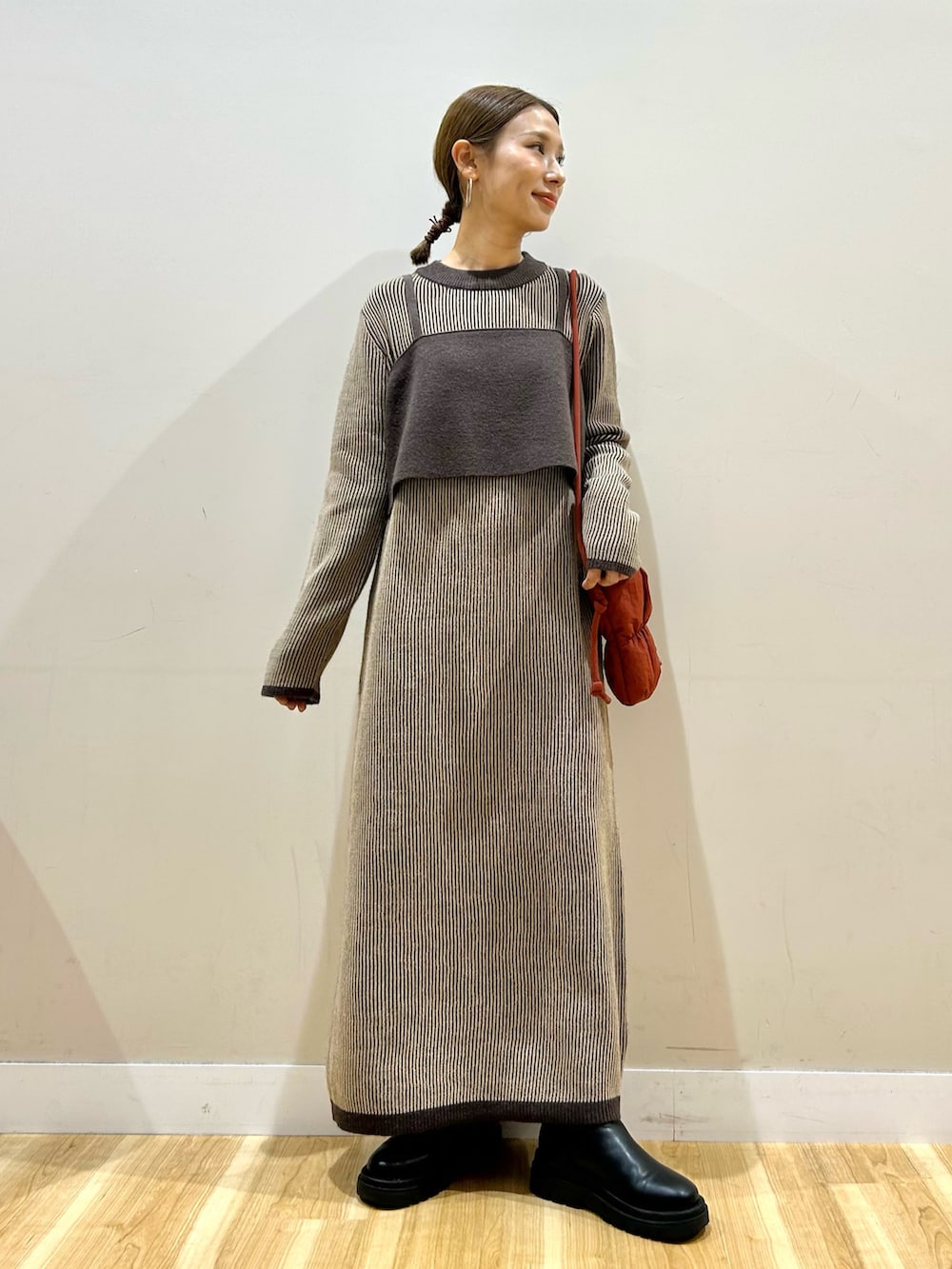 レッド系のショルダーバッグ、ベージュ系のワンピースを着用したレディースの冬コーディネートの4枚目の写真