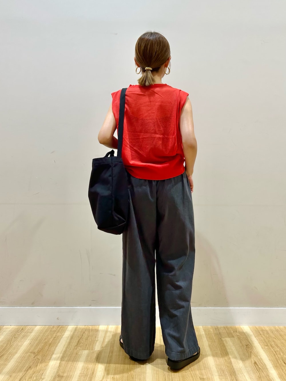 レッド系のニット/セーター、ブラック系のデニムパンツ、ブラック系のサンダルを着用したレディースの夏コーディネートの3枚目の写真