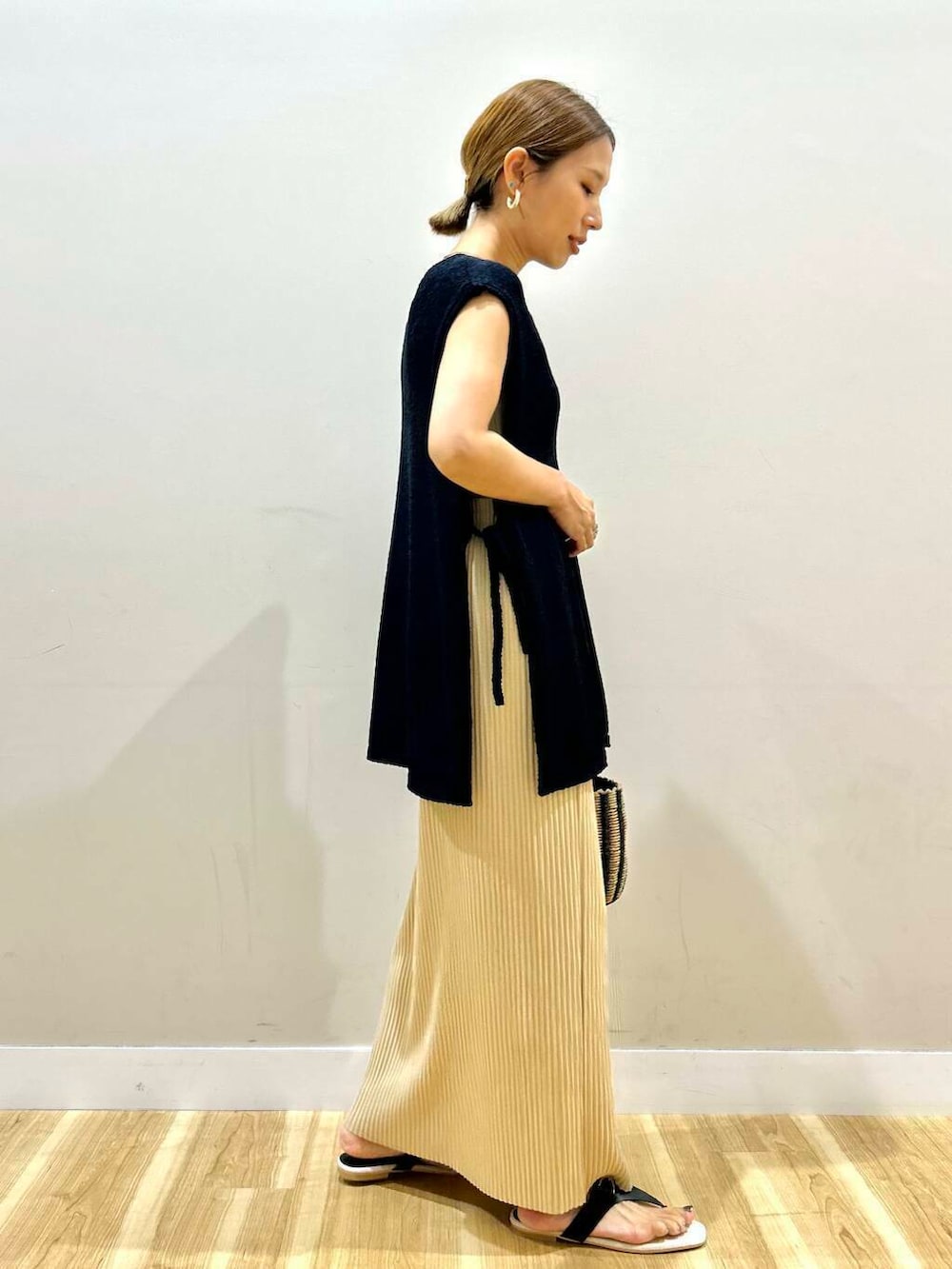 ベージュ系のタンクトップ、ブラック系のハンドバッグ、ブラック系のサンダルを着用したレディースの夏コーディネートの3枚目の写真