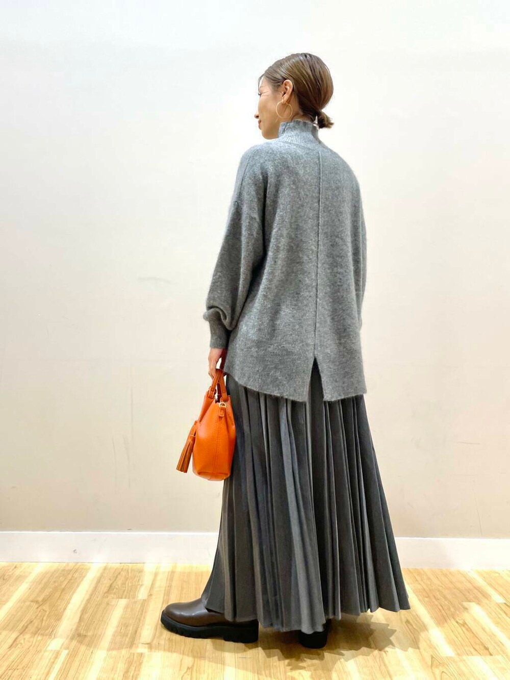 ブラウン系のブーツ、オレンジ系のショルダーバッグ、グレー系のスカートを着用したレディースの冬コーディネートの8枚目の写真