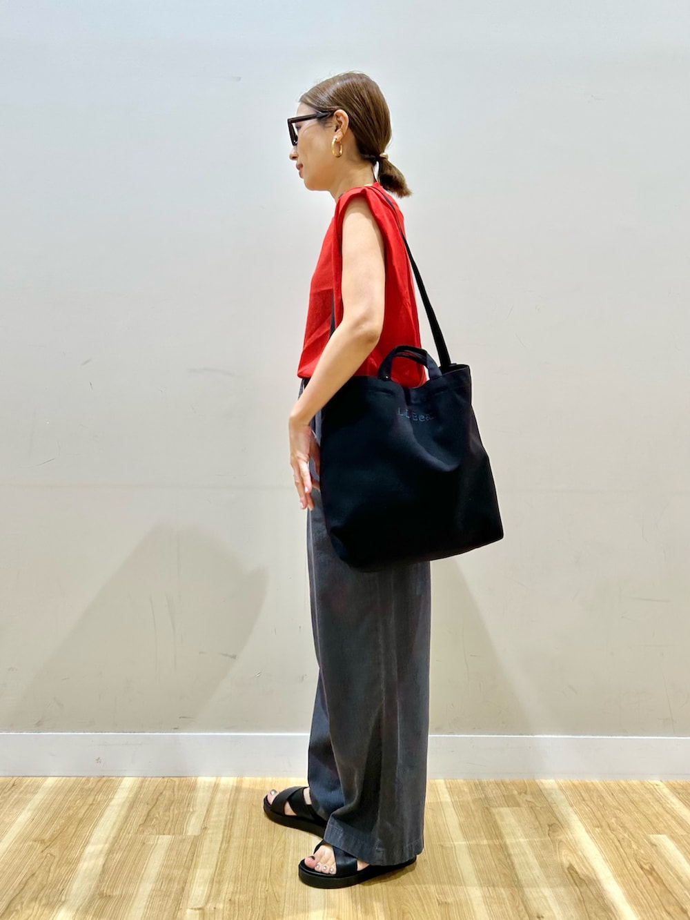 レッド系のニット/セーター、ブラック系のデニムパンツ、ブラック系のサンダルを着用したレディースの夏コーディネートの2枚目の写真