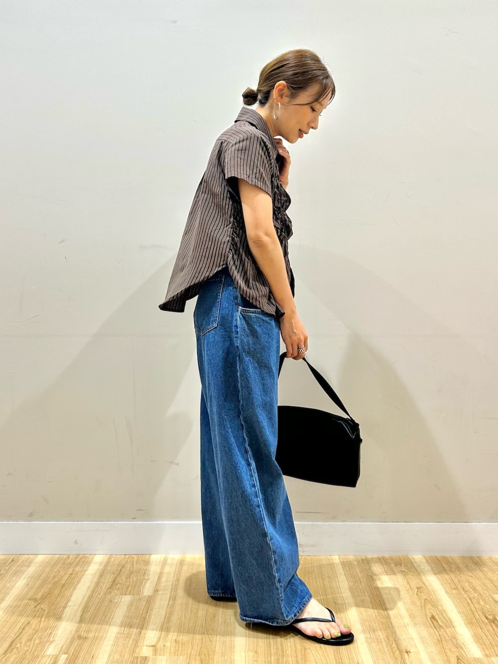ブラウン系のシャツ/ブラウス、ブルー系のデニムパンツ、ブラック系のトートバッグを着用したレディースの夏コーディネートの2枚目の写真