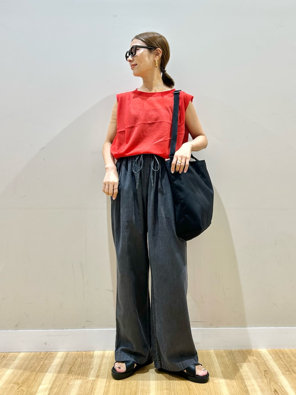 レッド系のニット/セーター、ブラック系のデニムパンツ、ブラック系のサンダルを着用したレディースの夏コーディネートの4枚目の写真