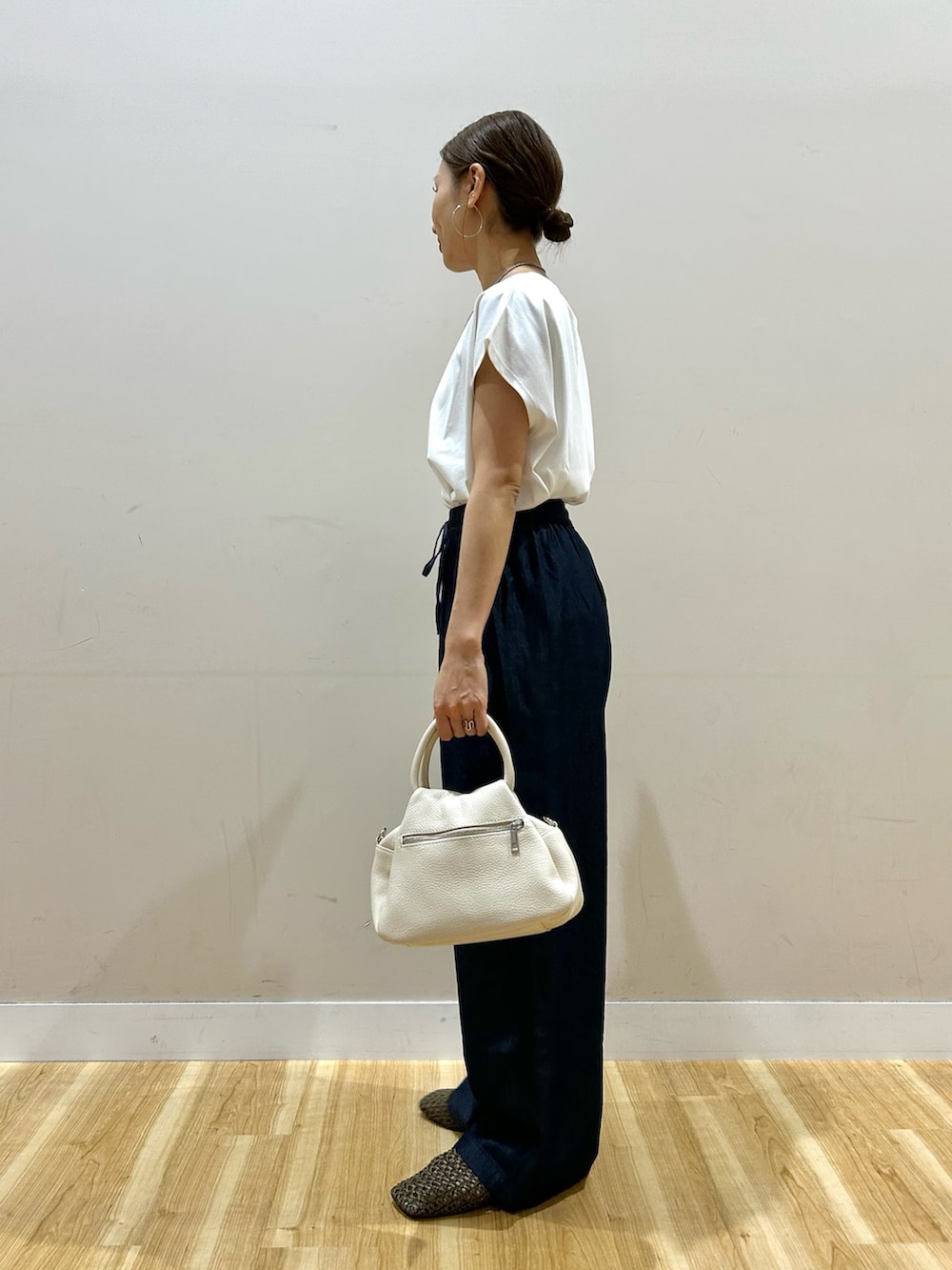 ホワイト系のTシャツ/カットソー、ブルー系のデニムパンツ、ブラウン系のハンドバッグを着用したレディースの春コーディネートの6枚目の写真