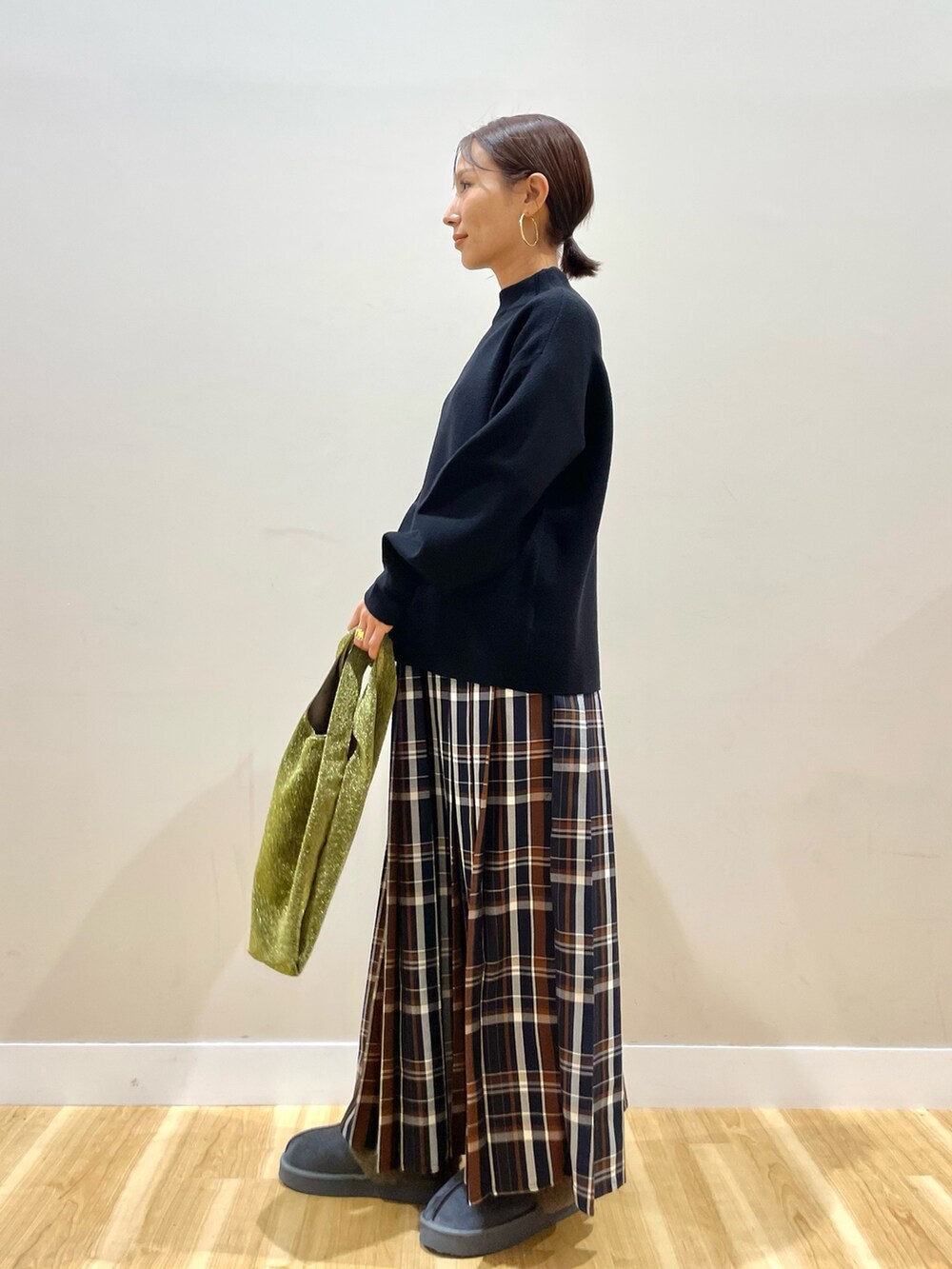 グレー系のノーカラーコート、ブラック系のニット/セーター、ブルー系のスカートを着用したレディースの冬コーディネートの5枚目の写真