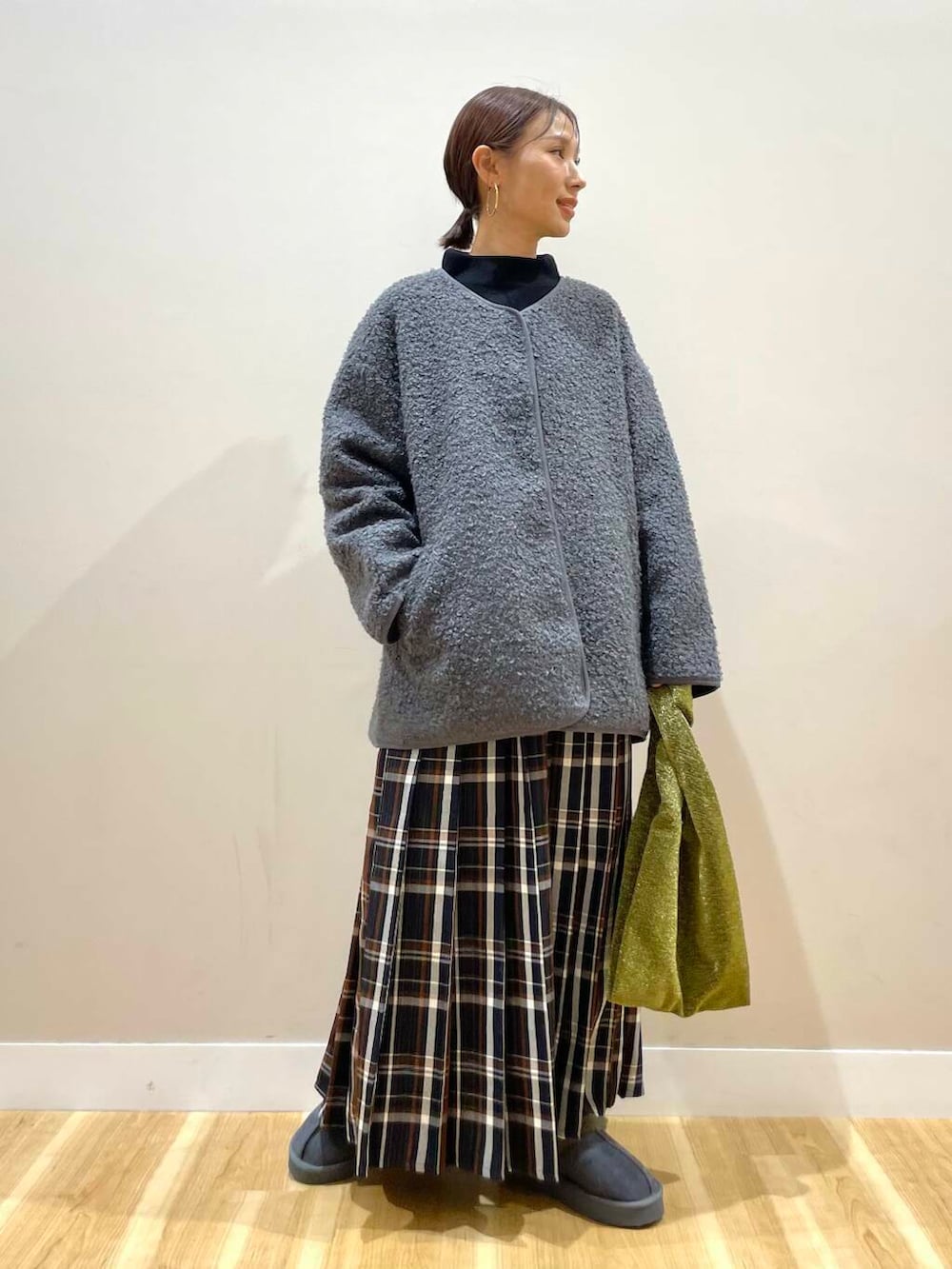 ゴールド系のトートバッグ、ブラック系のニット/セーター、ブルー系のスカートを着用したレディースの冬コーディネートの2枚目の写真