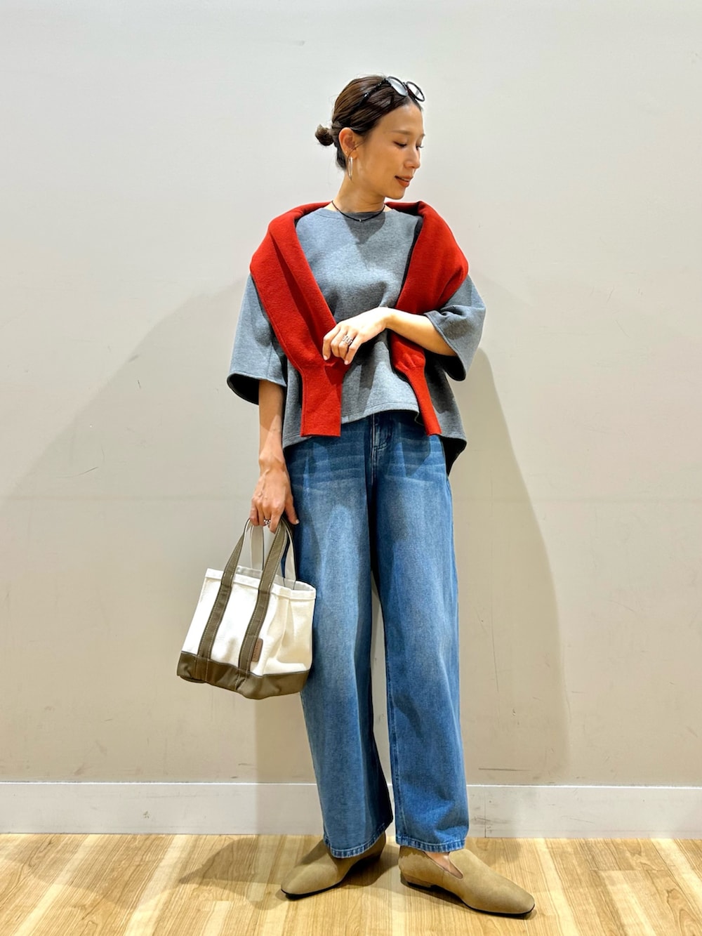 レッド系のニット/セーター、グレー系のTシャツ/カットソー、グレー系のトートバッグを着用したレディースの秋コーディネートの5枚目の写真