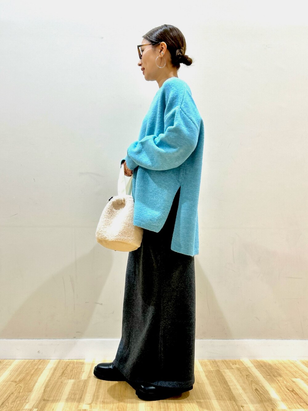 ブラック系のダウンジャケット/コート、ブルー系のニット/セーター、グレー系のスカートを着用したレディースの冬コーディネートの7枚目の写真