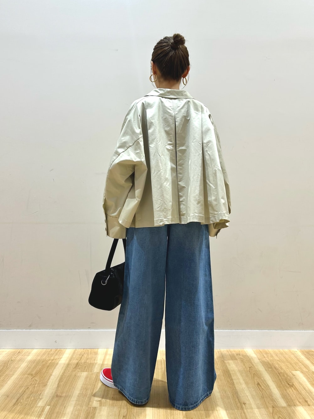 グレー系のステンカラーコート、グレー系のTシャツ/カットソー、ブルー系のデニムパンツを着用したレディースの春コーディネートの3枚目の写真