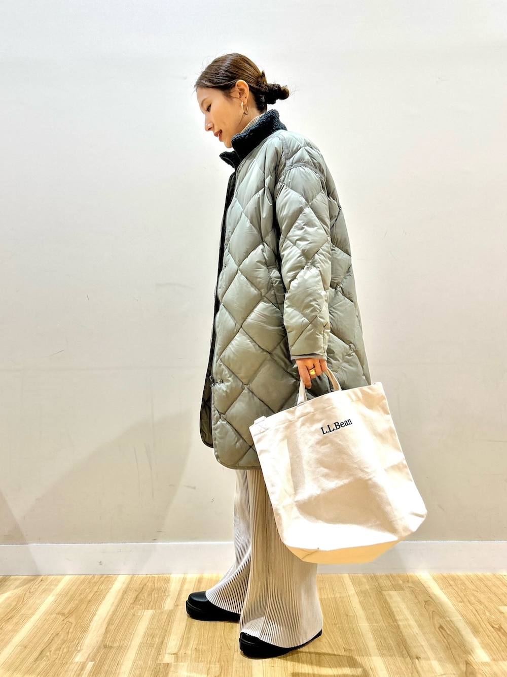 グレー系のベスト、グリーン系のダウンジャケット/コート、ホワイト系のニット/セーターを着用したレディースの冬コーディネートの2枚目の写真