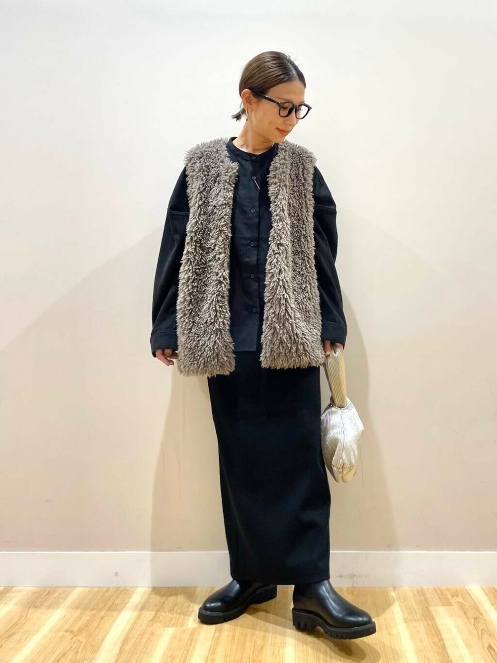 ブラック系のブーツ、グレー系のベスト、ゴールド系のハンドバッグを着用したレディースの秋コーディネートの6枚目の写真