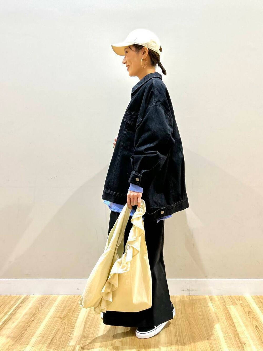 ブラック系のスニーカー、ホワイト系のトートバッグ、ブラック系のデニムジャケットを着用したレディースの春コーディネートの6枚目の写真