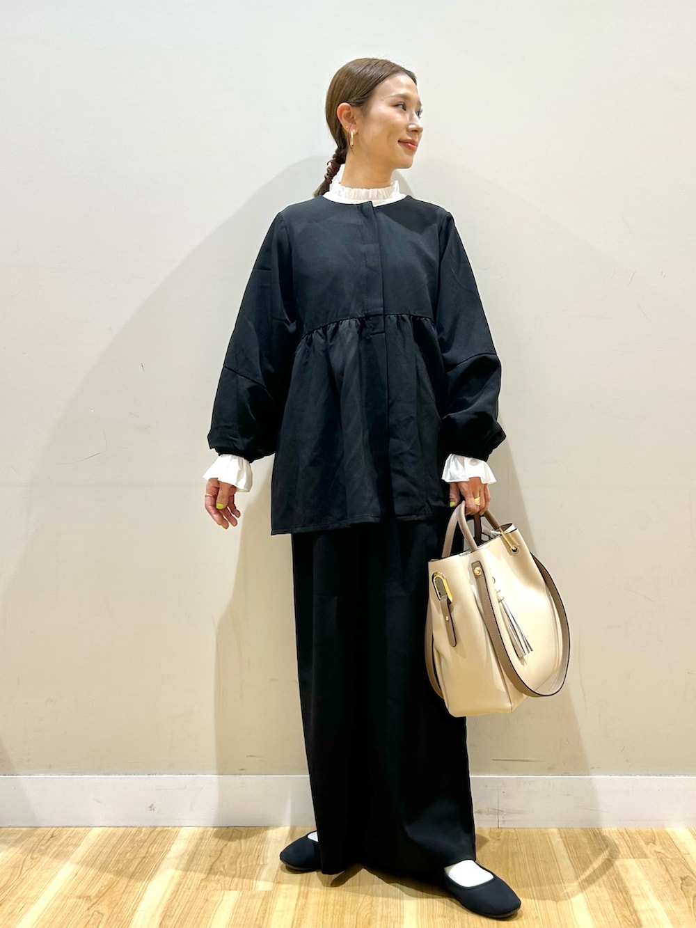 ブラック系のセットアップ、ホワイト系のトートバッグを着用したレディースの秋コーディネートの6枚目の写真