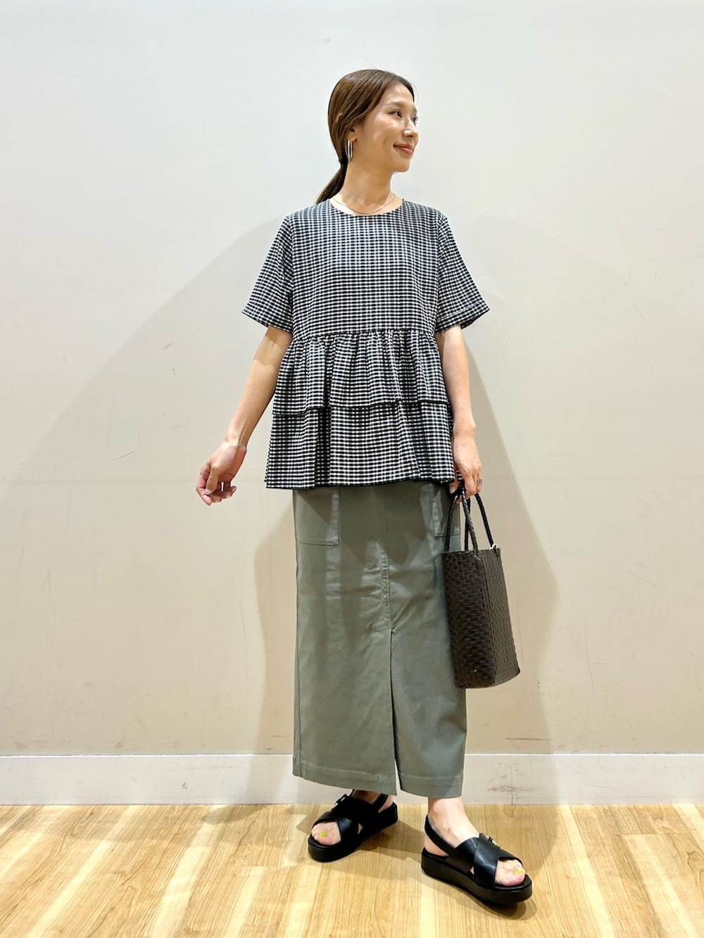 ブラック系のシャツ/ブラウス、グリーン系のスカート、ブラウン系のトートバッグを着用したレディースの夏コーディネートの4枚目の写真