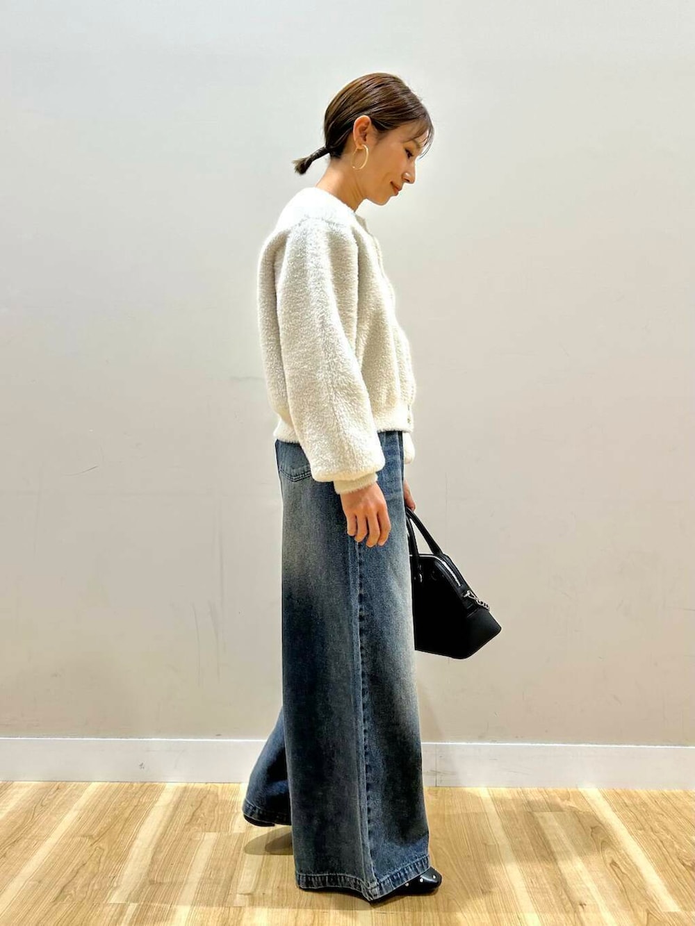 ブラック系のボストンバッグ、ブラック系のパンプス、ホワイト系のカーディガン/ボレロを着用したレディースの冬コーディネートの3枚目の写真