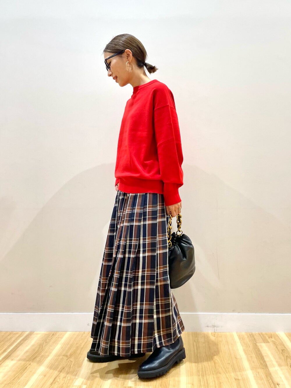 レッド系のニット/セーター、ブルー系のスカートを着用したレディースの秋コーディネートの5枚目の写真