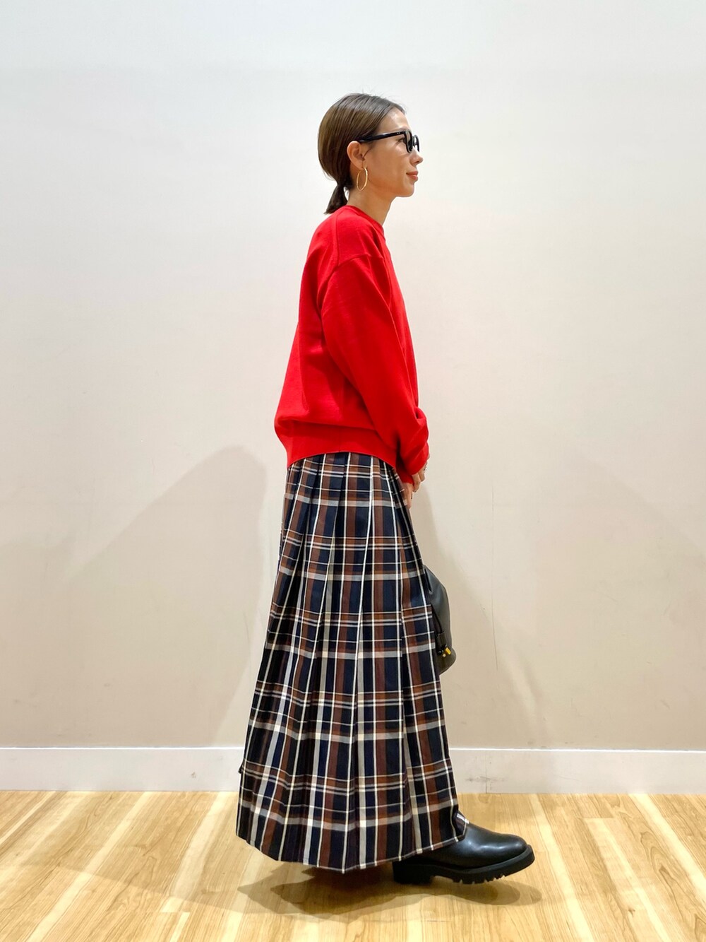 レッド系のニット/セーター、ブルー系のスカートを着用したレディースの秋コーディネートの2枚目の写真