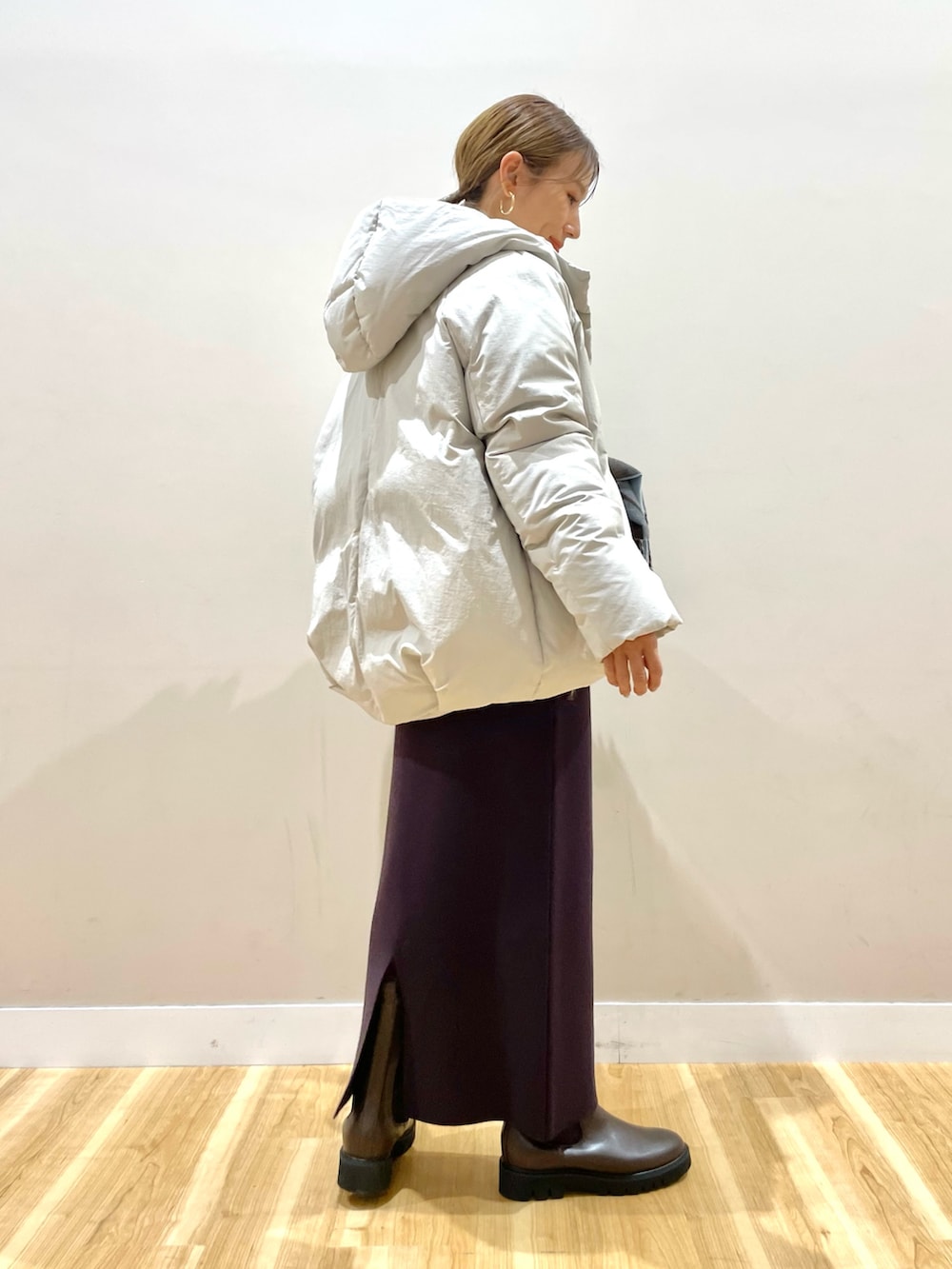 ホワイト系のダウンジャケット/コート、グレー系のニット/セーター、ブラウン系のスカートを着用したレディースの冬コーディネートの3枚目の写真