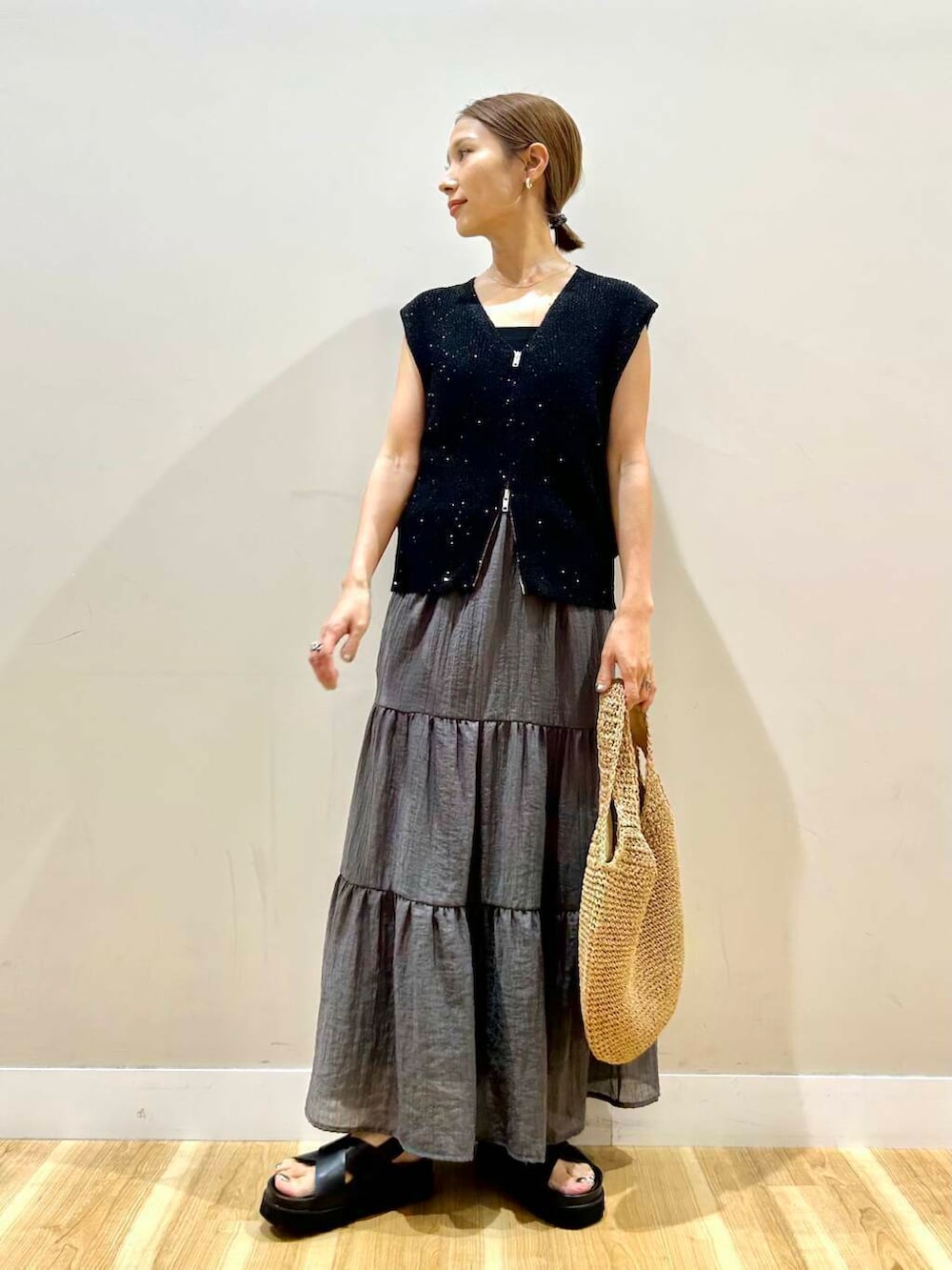 イエロー系のトートバッグ、ブラック系のサンダル、ブラック系のベストを着用したレディースの夏コーディネートの4枚目の写真