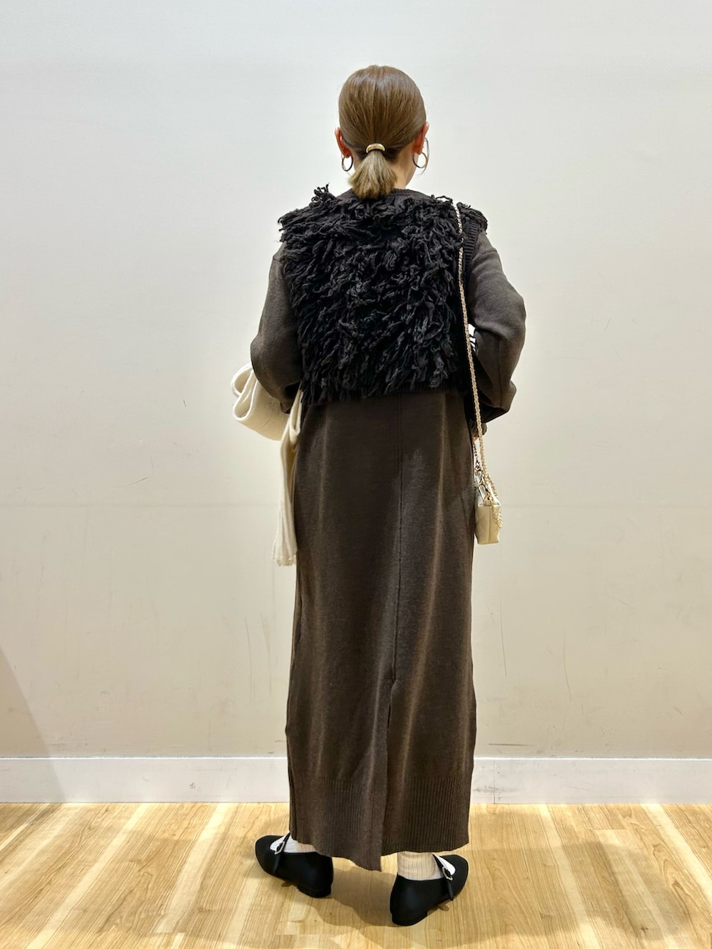 ブラウン系のワンピース、ホワイト系のショルダーバッグ、ブラック系のパンプスを着用したレディースの秋コーディネートの3枚目の写真