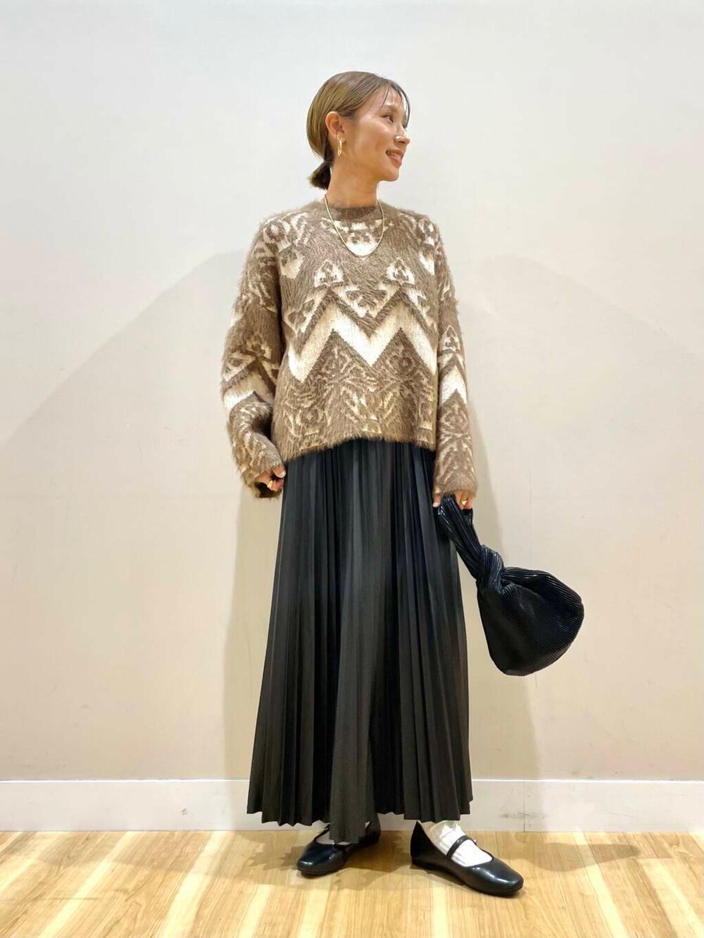 ブラック系のパンプス、ブラック系のハンドバッグ、ベージュ系のカーディガン/ボレロを着用したレディースの冬コーディネートの7枚目の写真