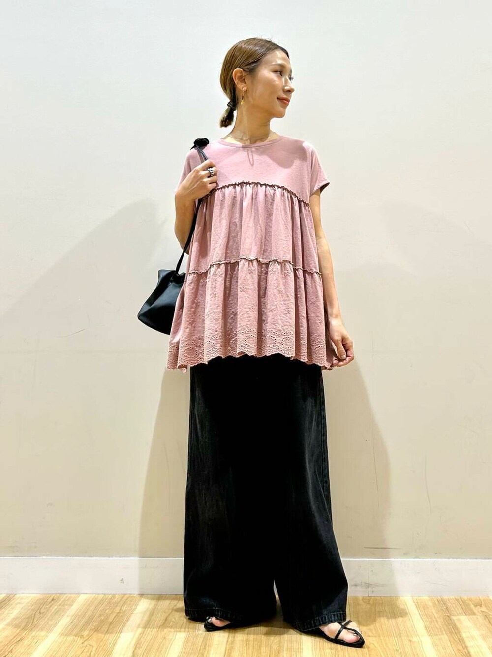 ブラック系のデニムパンツ、ブラック系のショルダーバッグ、ピンク系のTシャツ/カットソーを着用したレディースの夏コーディネートの5枚目の写真