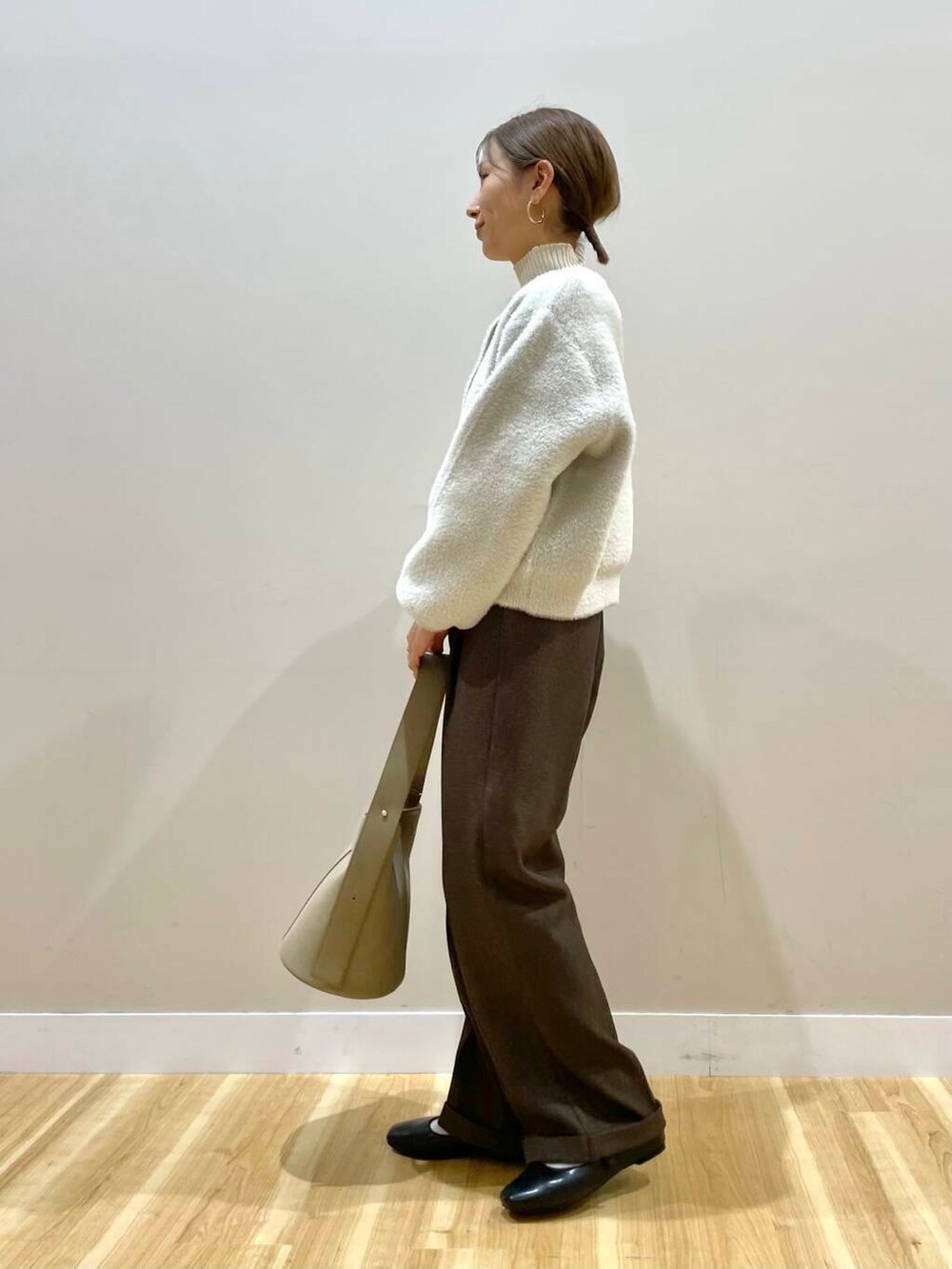 ブラック系のパンプス、ホワイト系のニット/セーター、ベージュ系のハンドバッグを着用したレディースの冬コーディネートの2枚目の写真