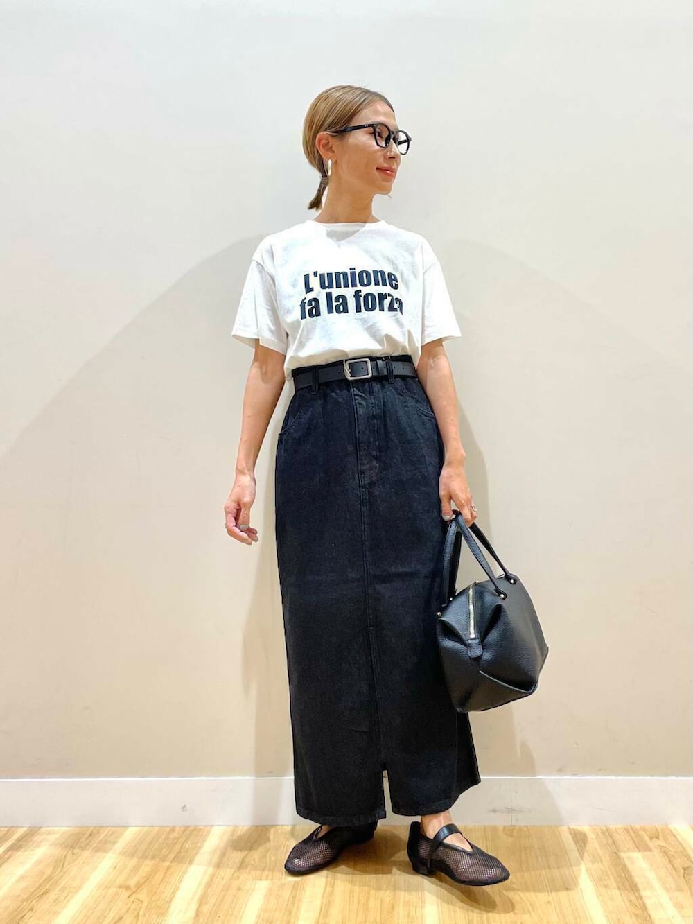 ブラック系のハンドバッグ、ブラック系のその他シューズ、ホワイト系のTシャツ/カットソーを着用したレディースの夏コーディネートの5枚目の写真