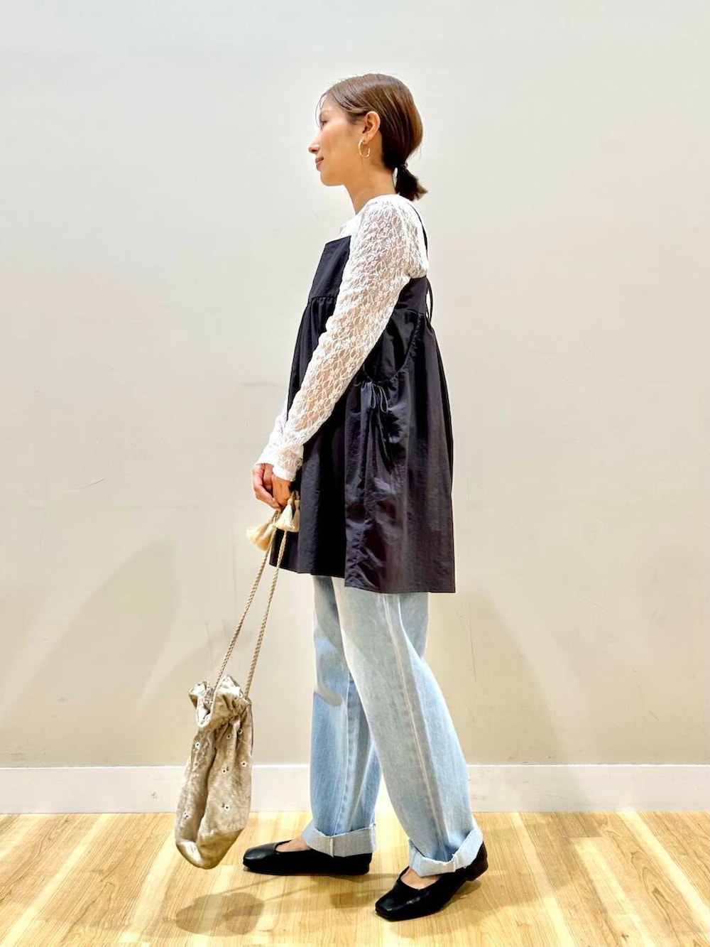 ブルー系のデニムパンツ、ベージュ系のショルダーバッグ、ブラック系のパンプスを着用したレディースの春コーディネートの2枚目の写真