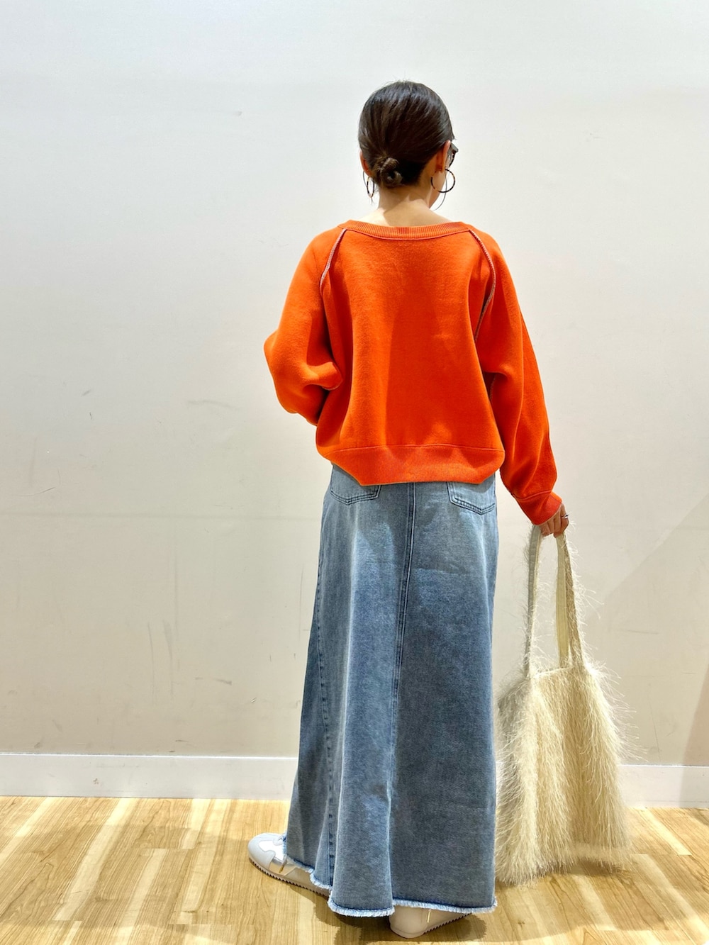 ブラック系のダウンジャケット/コート、オレンジ系のニット/セーター、ブルー系のスカートを着用したレディースの冬コーディネートの7枚目の写真