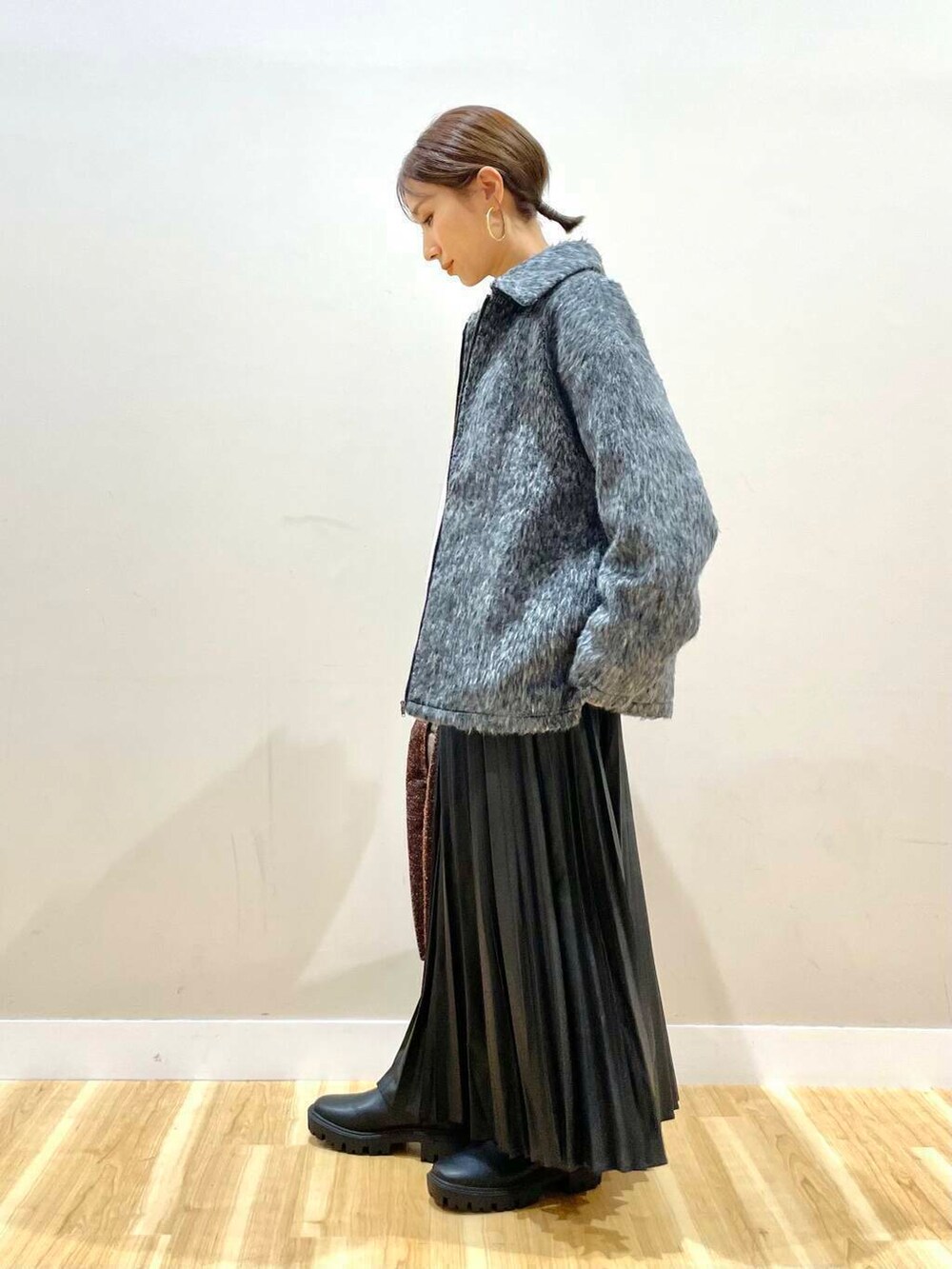 ブラック系のブーツ、ホワイト系のニット/セーター、ブラウン系のトートバッグを着用したレディースの冬コーディネートの2枚目の写真