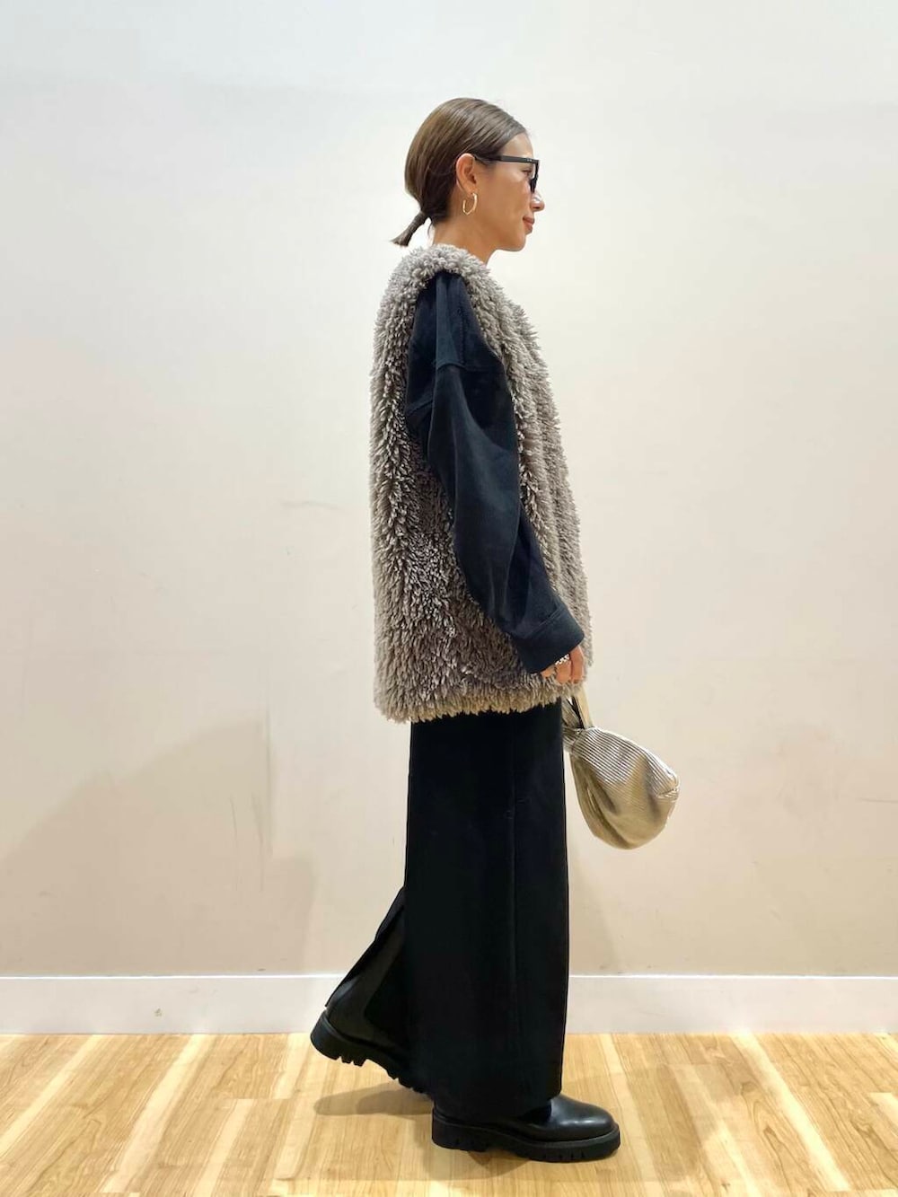 ブラック系のブーツ、グレー系のベスト、ゴールド系のハンドバッグを着用したレディースの秋コーディネートの3枚目の写真