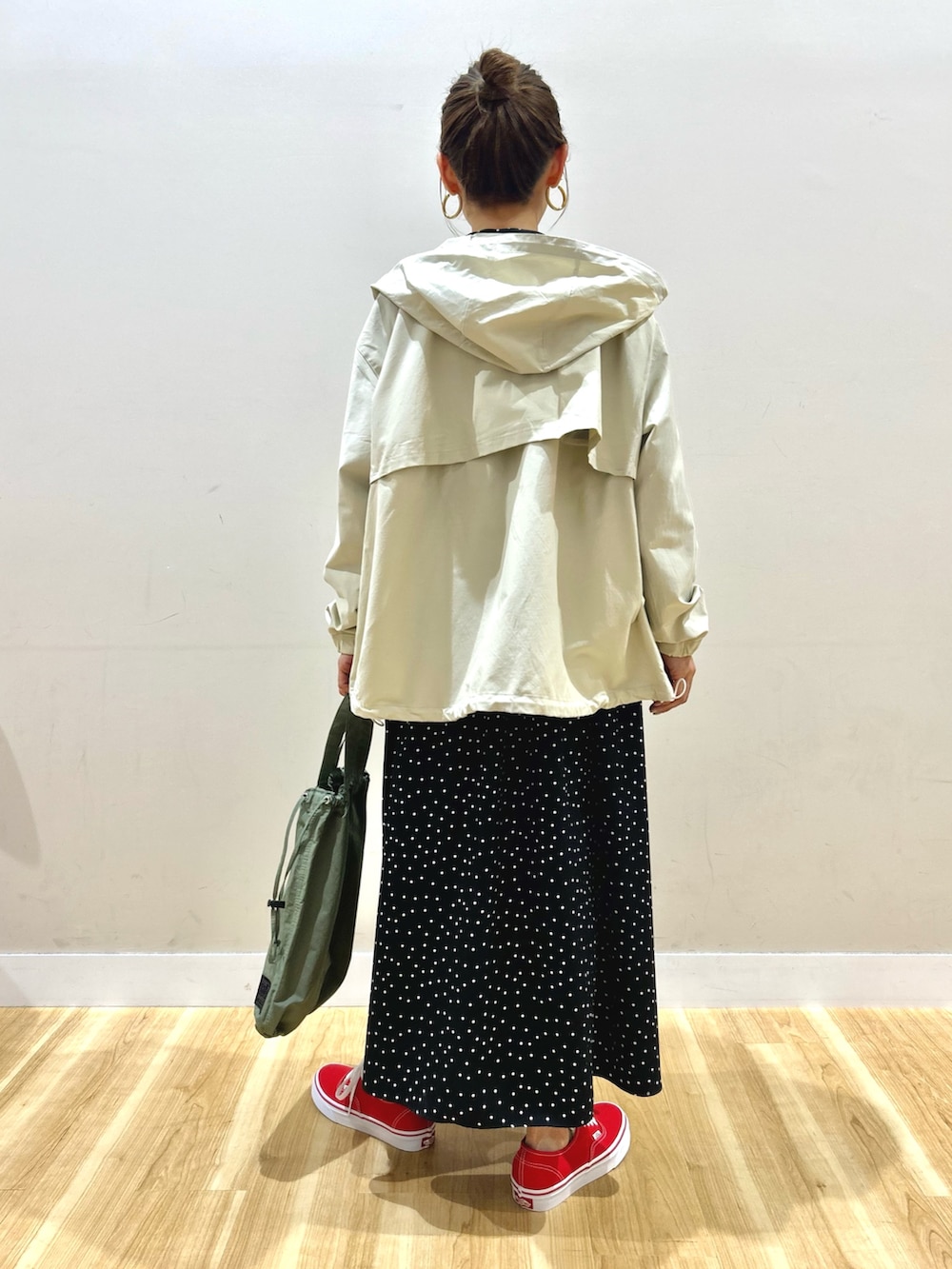 ホワイト系のマウンテンパーカー、ブラック系のワンピース、グリーン系のショルダーバッグを着用したレディースの春コーディネートの4枚目の写真