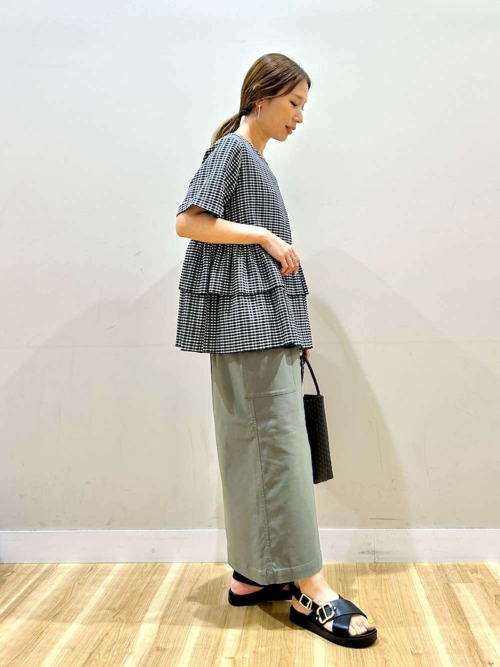 ブラック系のシャツ/ブラウス、グリーン系のスカート、ブラウン系のトートバッグを着用したレディースの夏コーディネートの2枚目の写真