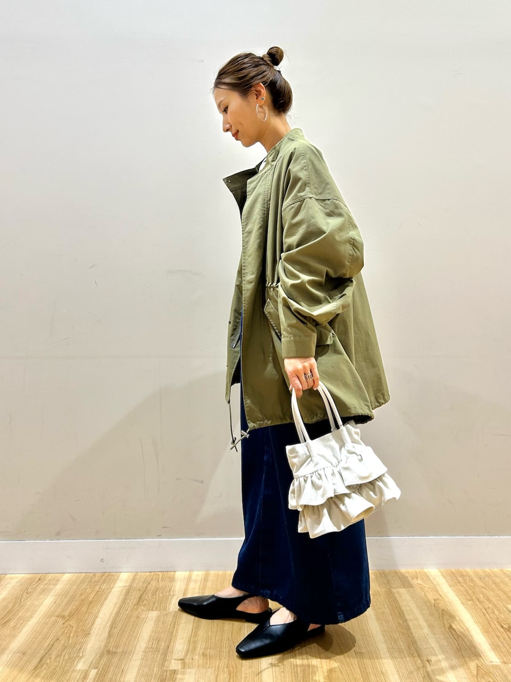 グリーン系のモッズコート、ブラック系のTシャツ/カットソー、ブルー系のワンピースを着用したレディースの春コーディネートの2枚目の写真