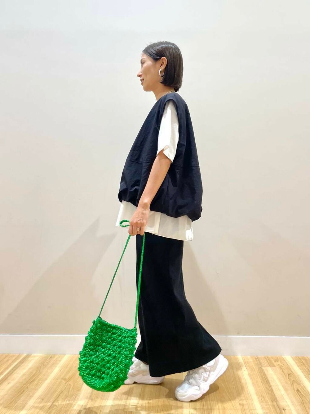 ホワイト系のスニーカー、グリーン系のショルダーバッグ、ブラック系のスカートを着用したレディースの秋コーディネートの5枚目の写真