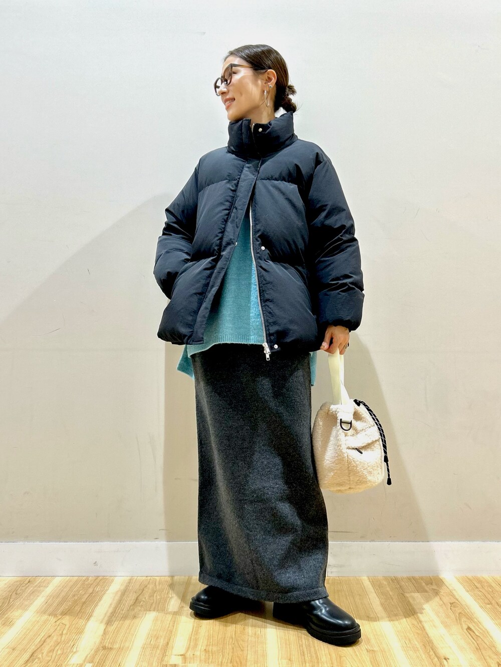 ブラック系のダウンジャケット/コート、ブルー系のニット/セーター、グレー系のスカートを着用したレディースの冬コーディネートの3枚目の写真