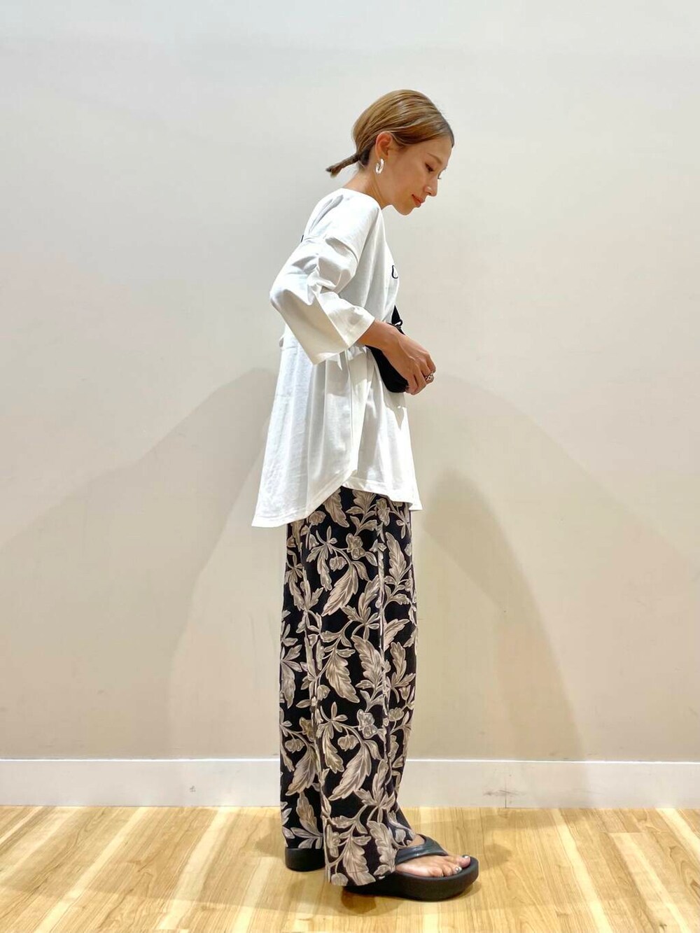 ブラック系のショルダーバッグ、ブラック系のその他パンツ、ホワイト系のTシャツ/カットソーを着用したレディースの夏コーディネートの2枚目の写真