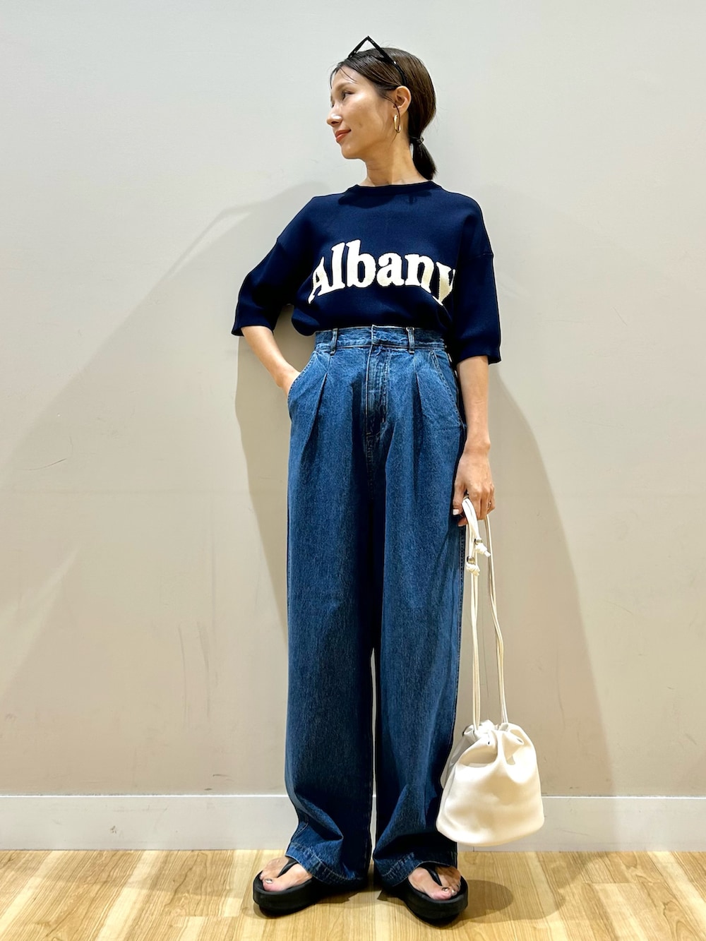 ブルー系のニット/セーター、ブルー系のデニムパンツ、ホワイト系のショルダーバッグを着用したレディースの夏コーディネートの2枚目の写真