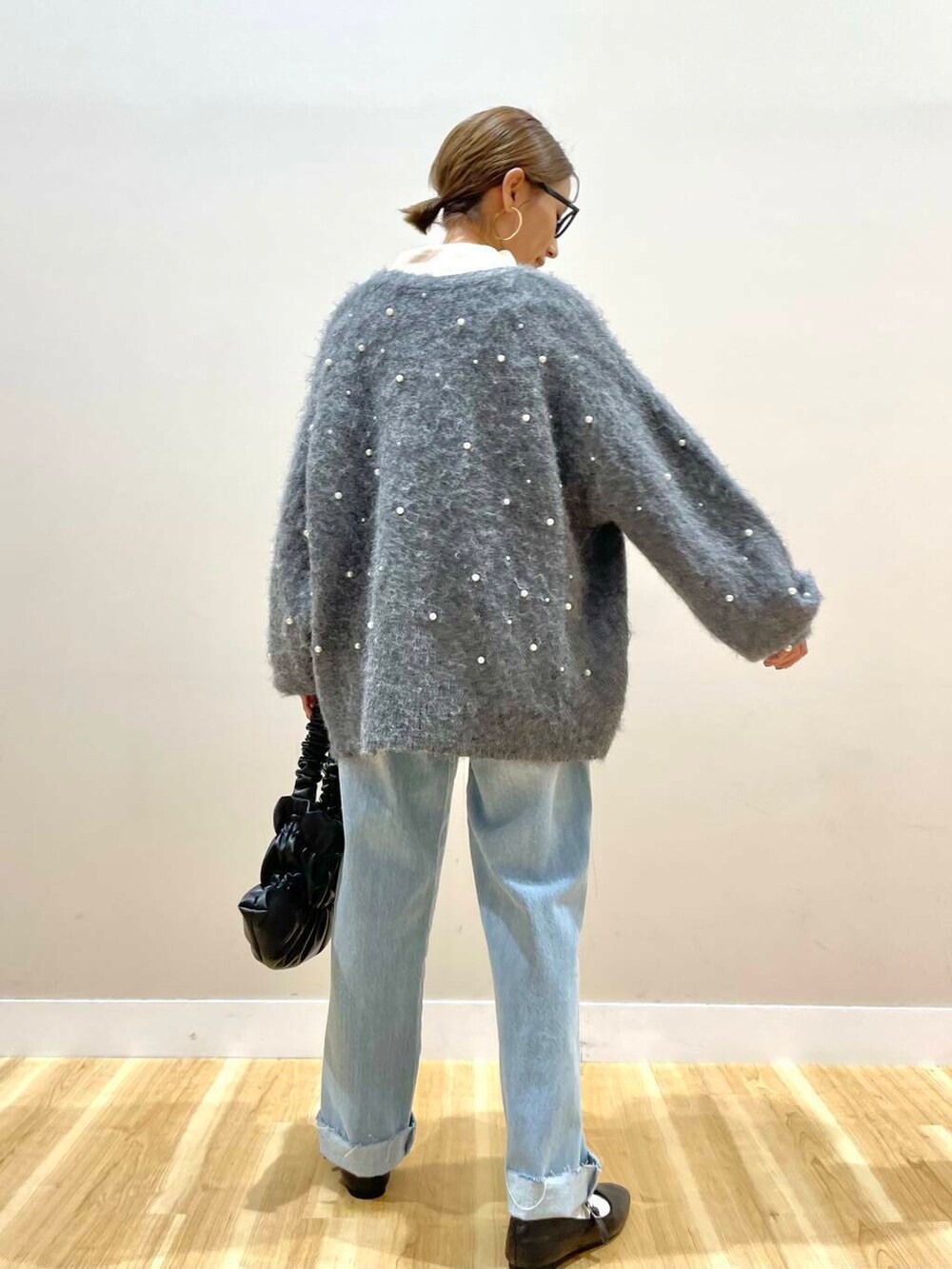 ブラック系のパンプス、ブラック系のハンドバッグ、ブルー系のデニムパンツを着用したレディースの秋コーディネートの4枚目の写真