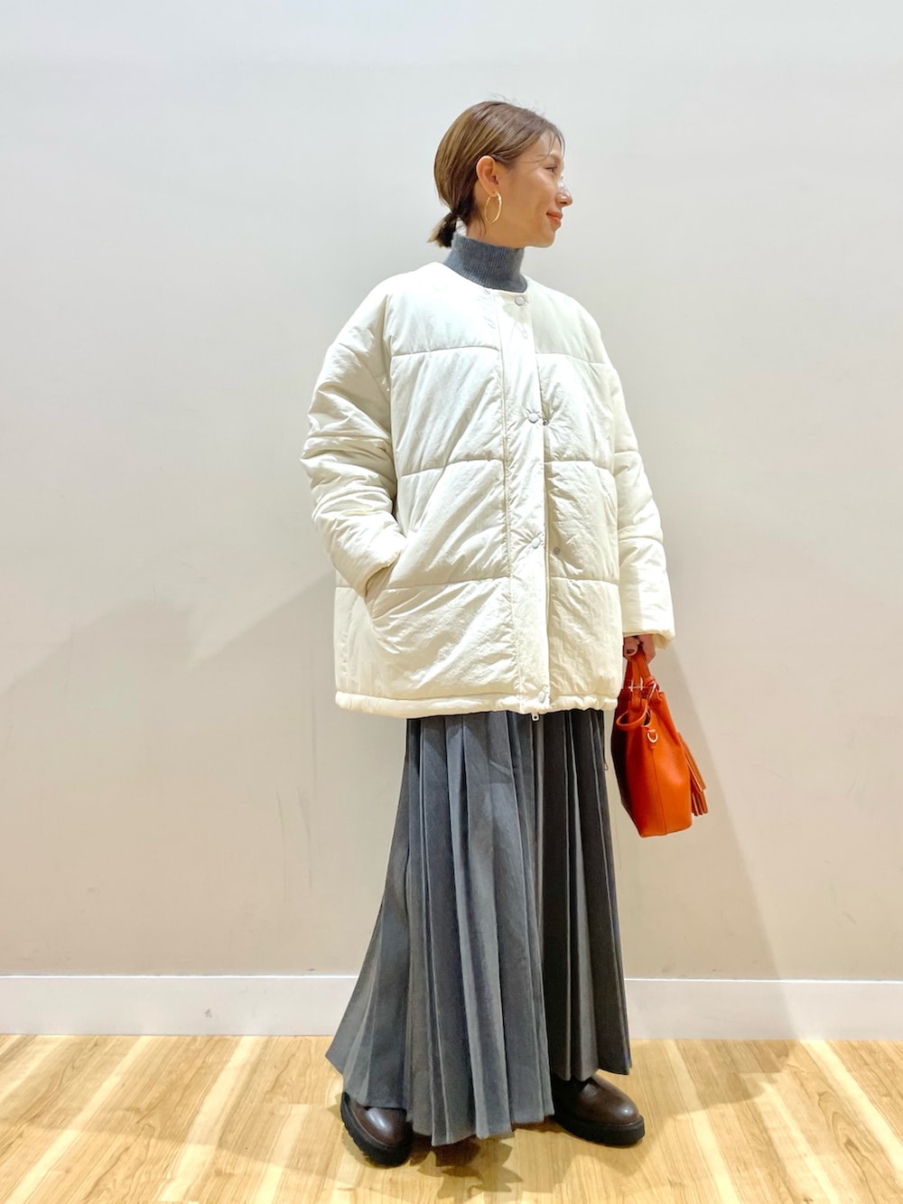 ホワイト系のダウンジャケット/コート、グレー系のニット/セーター、グレー系のスカートを着用したレディースの冬コーディネートの3枚目の写真