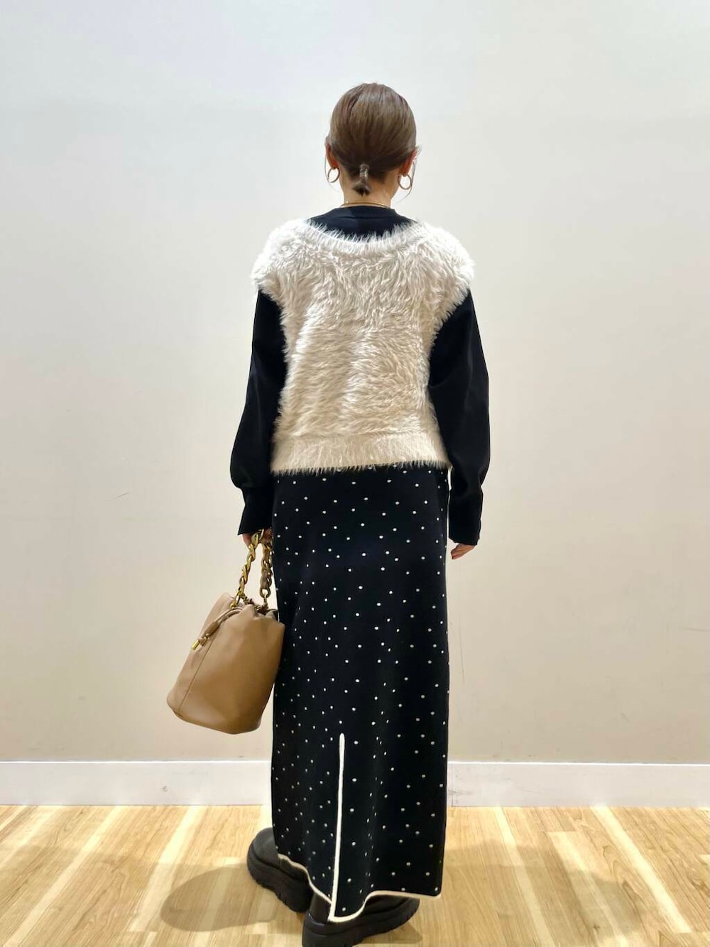 ブラウン系のショルダーバッグ、ブラック系のニット/セーター、ブラック系のスカートを着用したレディースの冬コーディネートの3枚目の写真